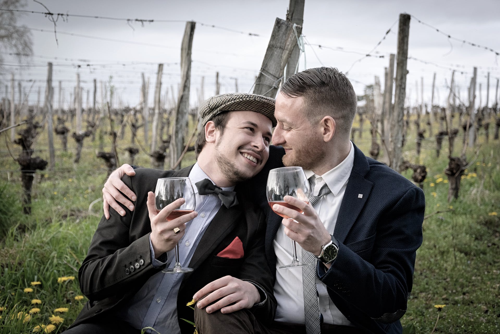 Deux jeunes hommes s'étreignent en buvant du vin | Source : Pexels