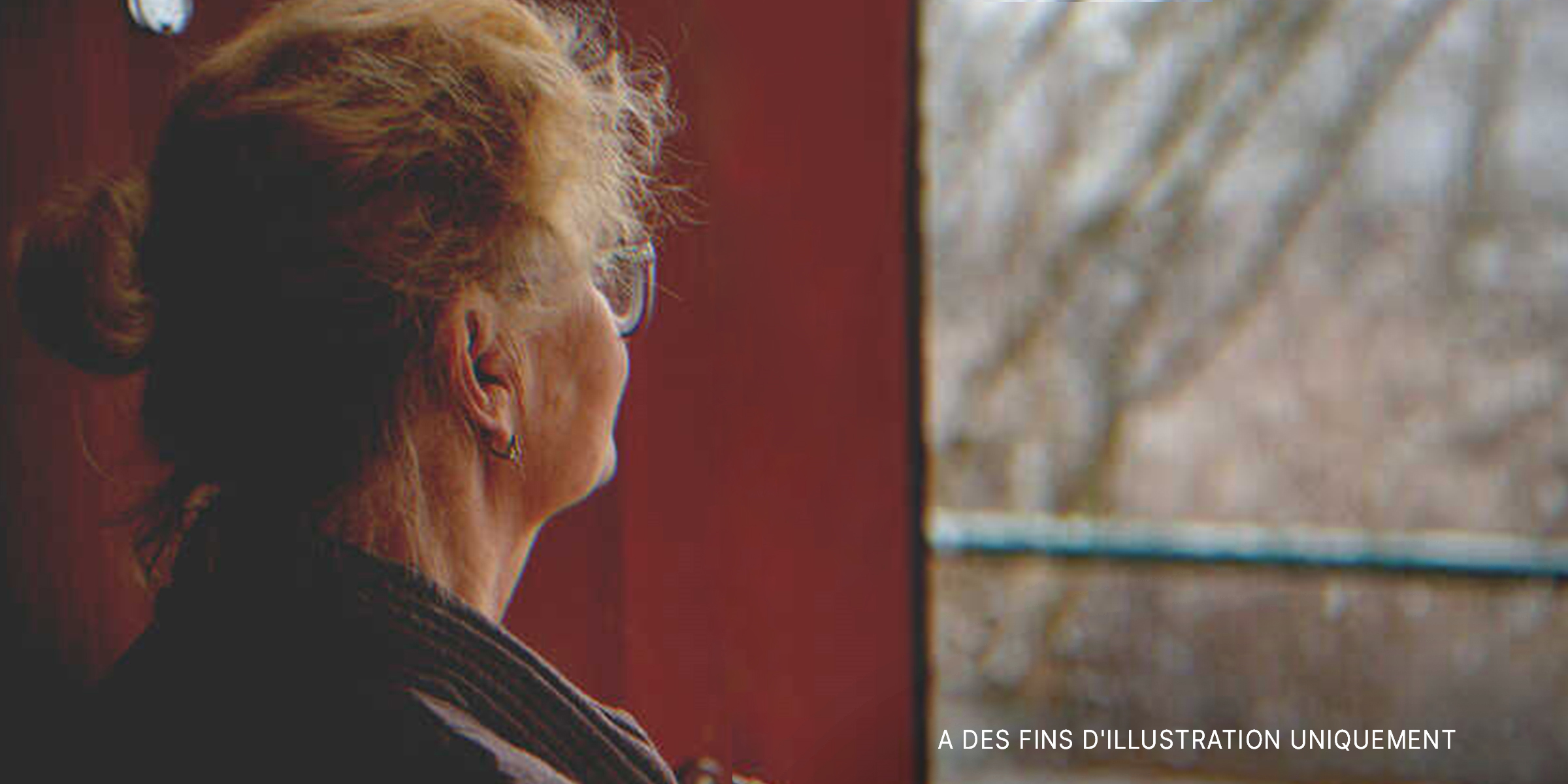Une femme âgée devant la fenêtre de sa maison | Source : Shutterstock