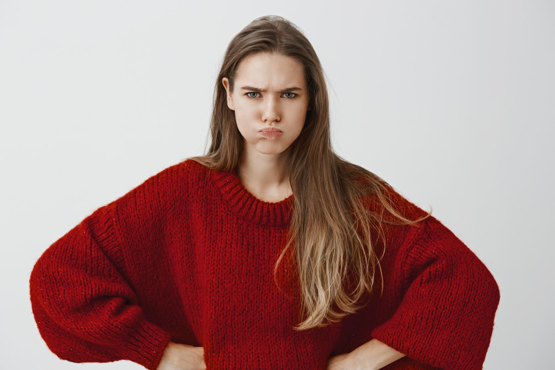 Une jeune femme en colère avec un pull rouge | Source : Freepik