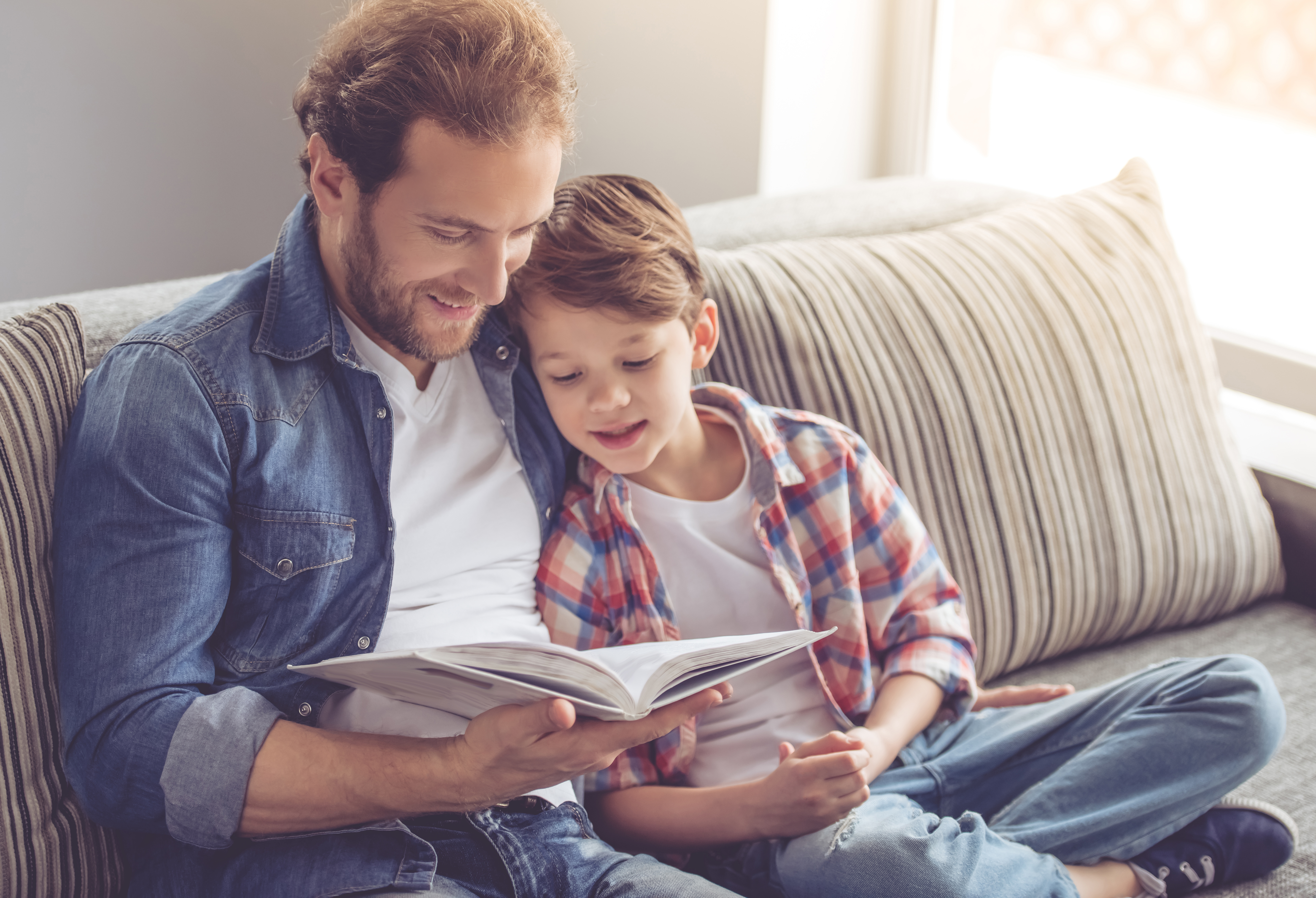 Père et fils lisant un livre et souriant | Source : Shutterstock