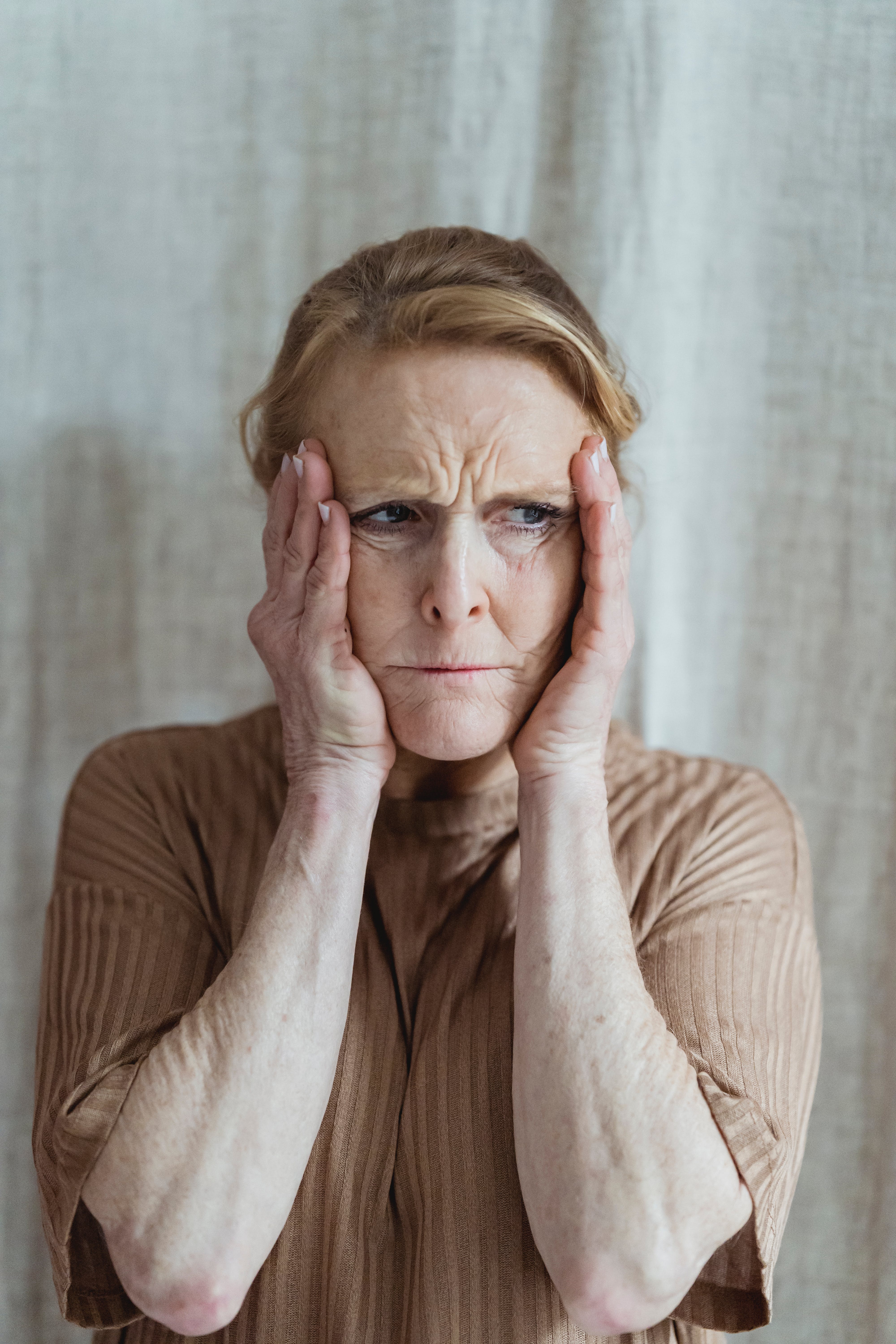 Une femme âgée en détresse se tenant le visage à deux mains | Source : Pexels