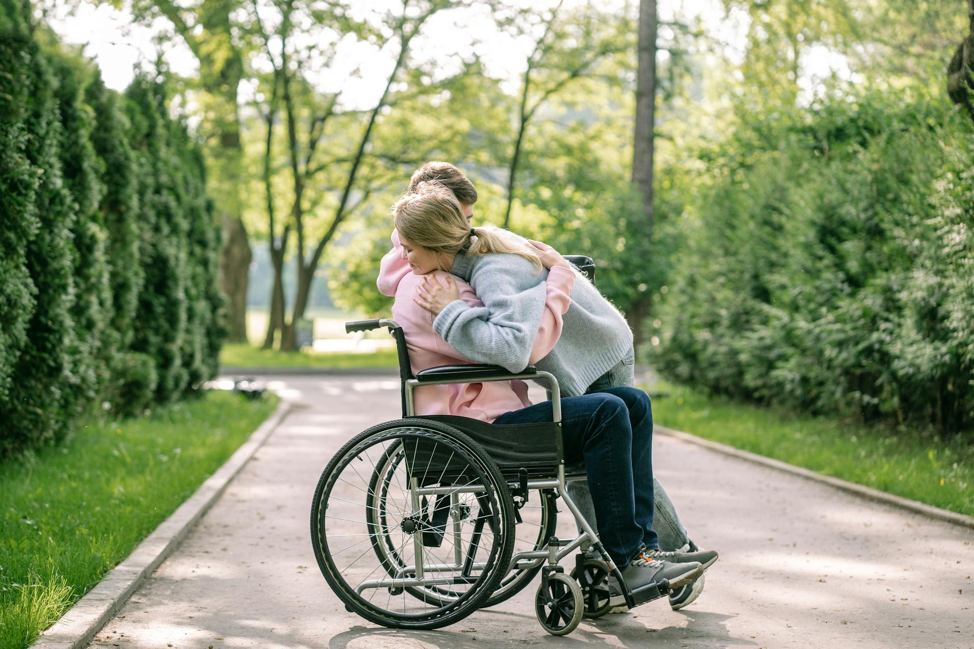 Une femme serrant dans ses bras un homme en fauteuil roulant | Source : Pexels