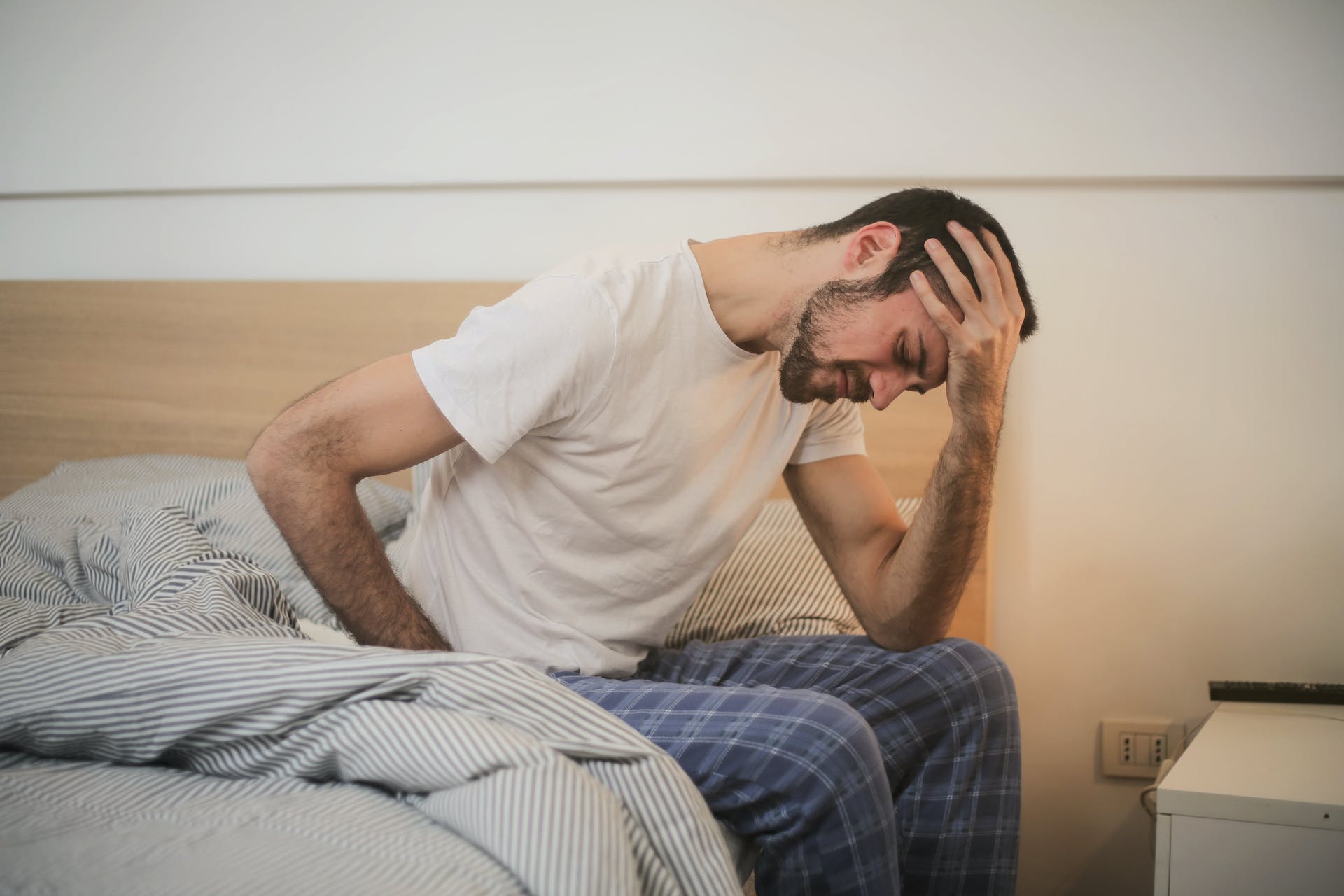 Un homme en détresse assis sur le côté de son lit | Source : Pexels