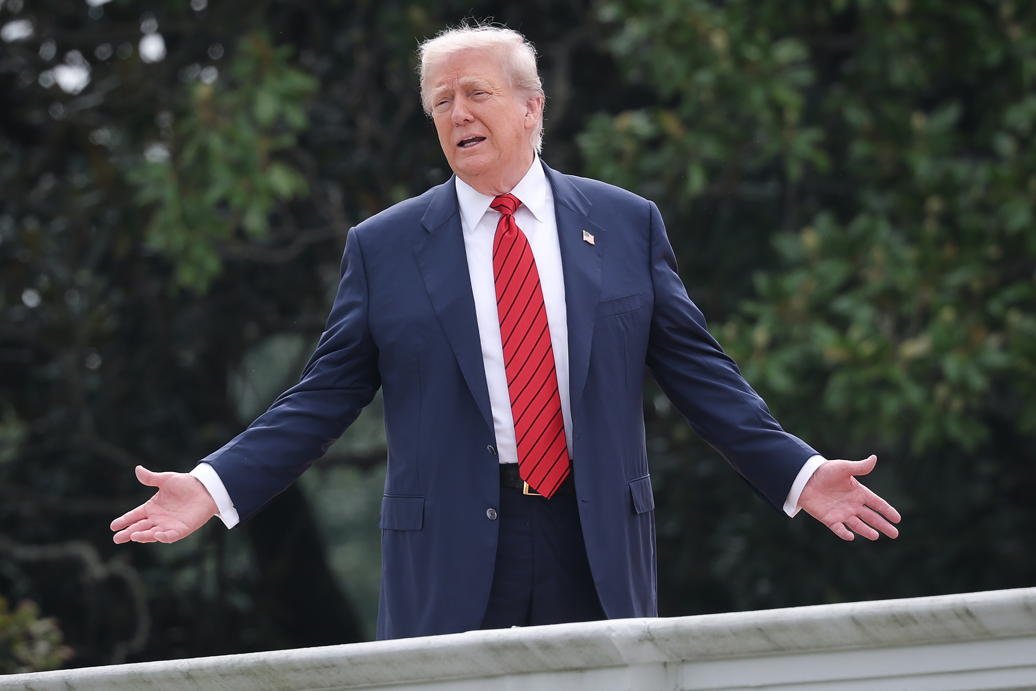 Lors d'une rare promenade sur le toit de l'aile ouest de la Maison Blanche, le président Donald Trump écarte les bras tout en répondant aux journalistes, faisant de ce moment un spectacle.