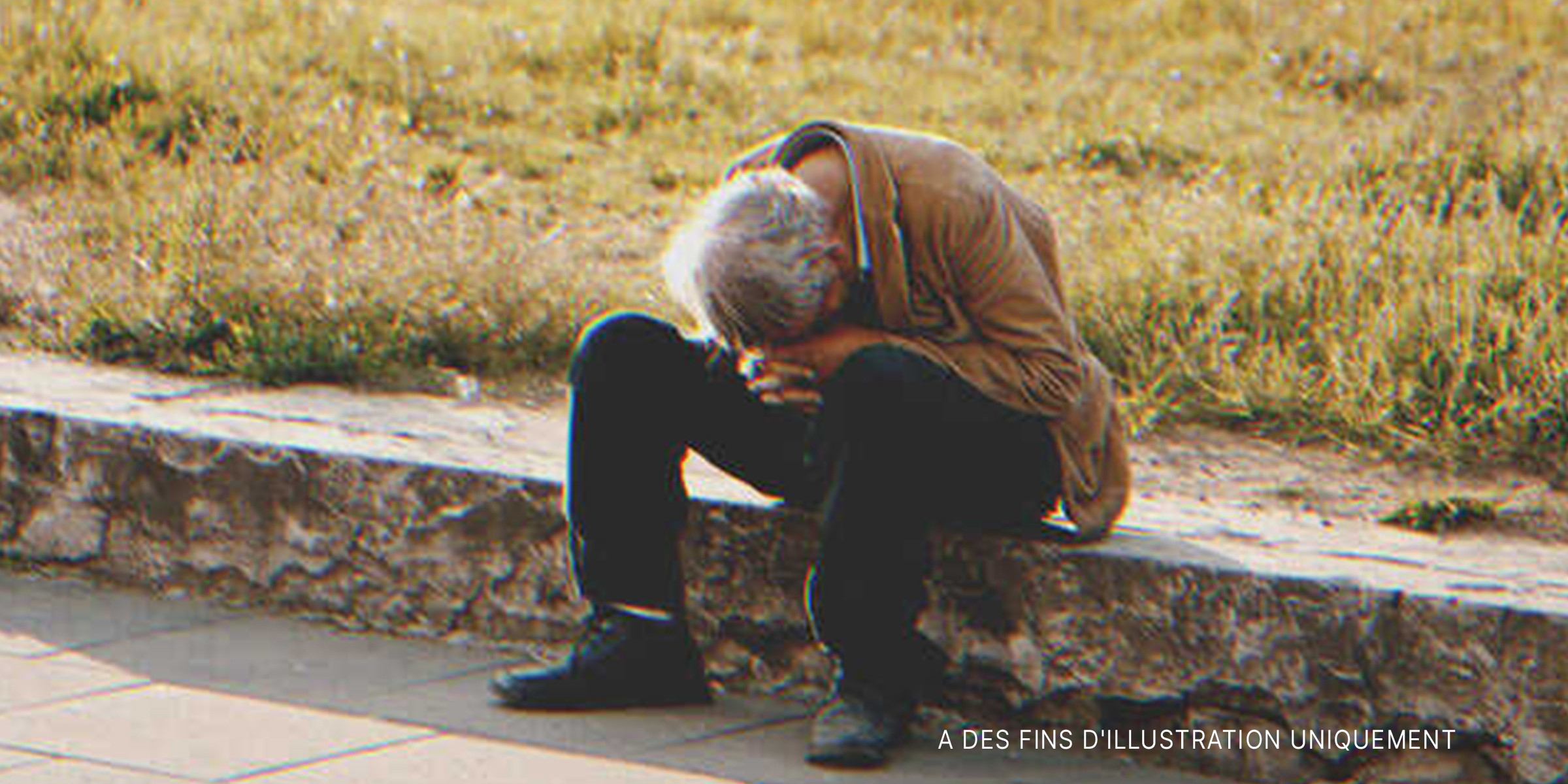 Un homme âgée assis sur un trottoir | Source : Shutterstock