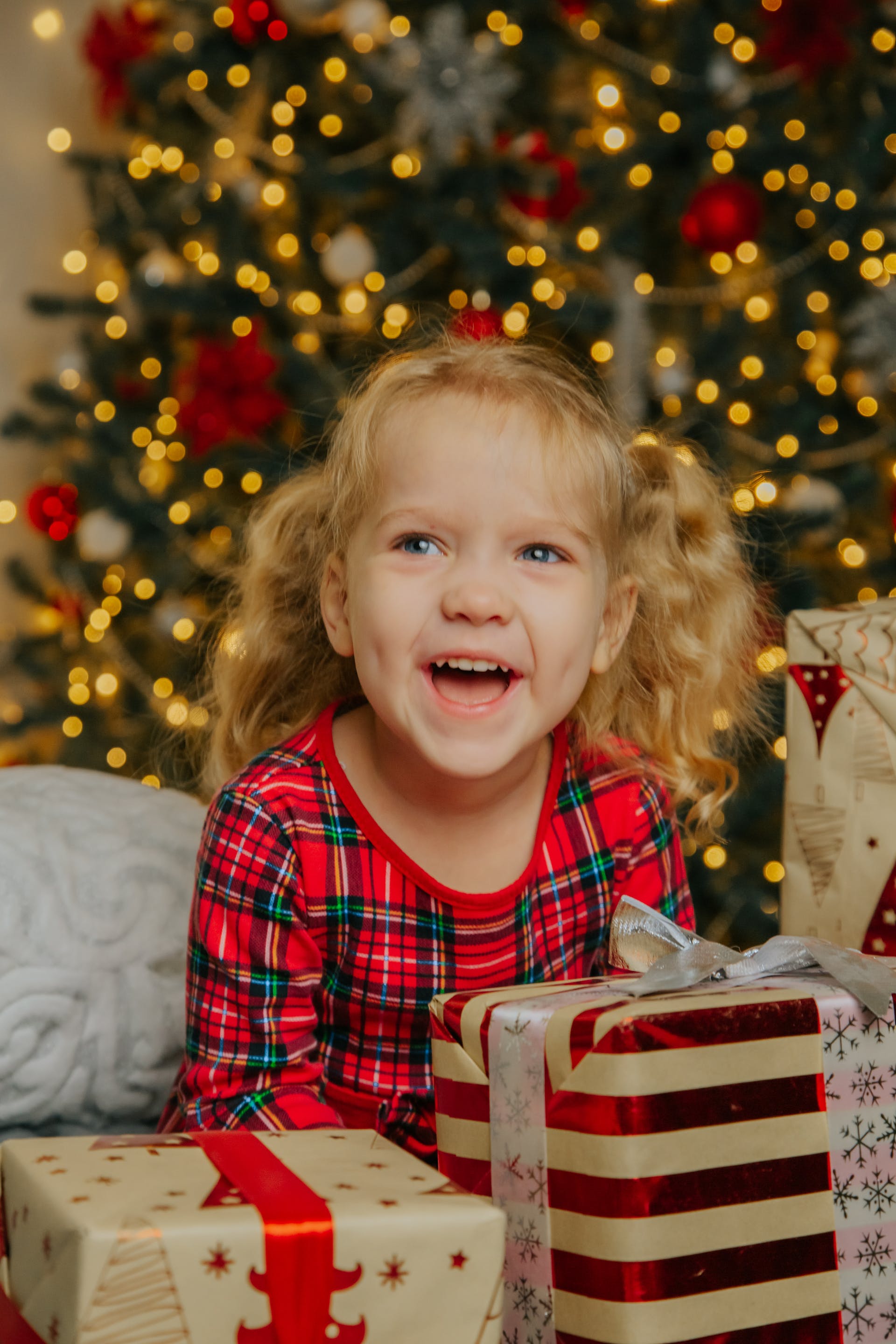 Une petite fille souriante tenant des cadeaux de Noël | Source : Pexels