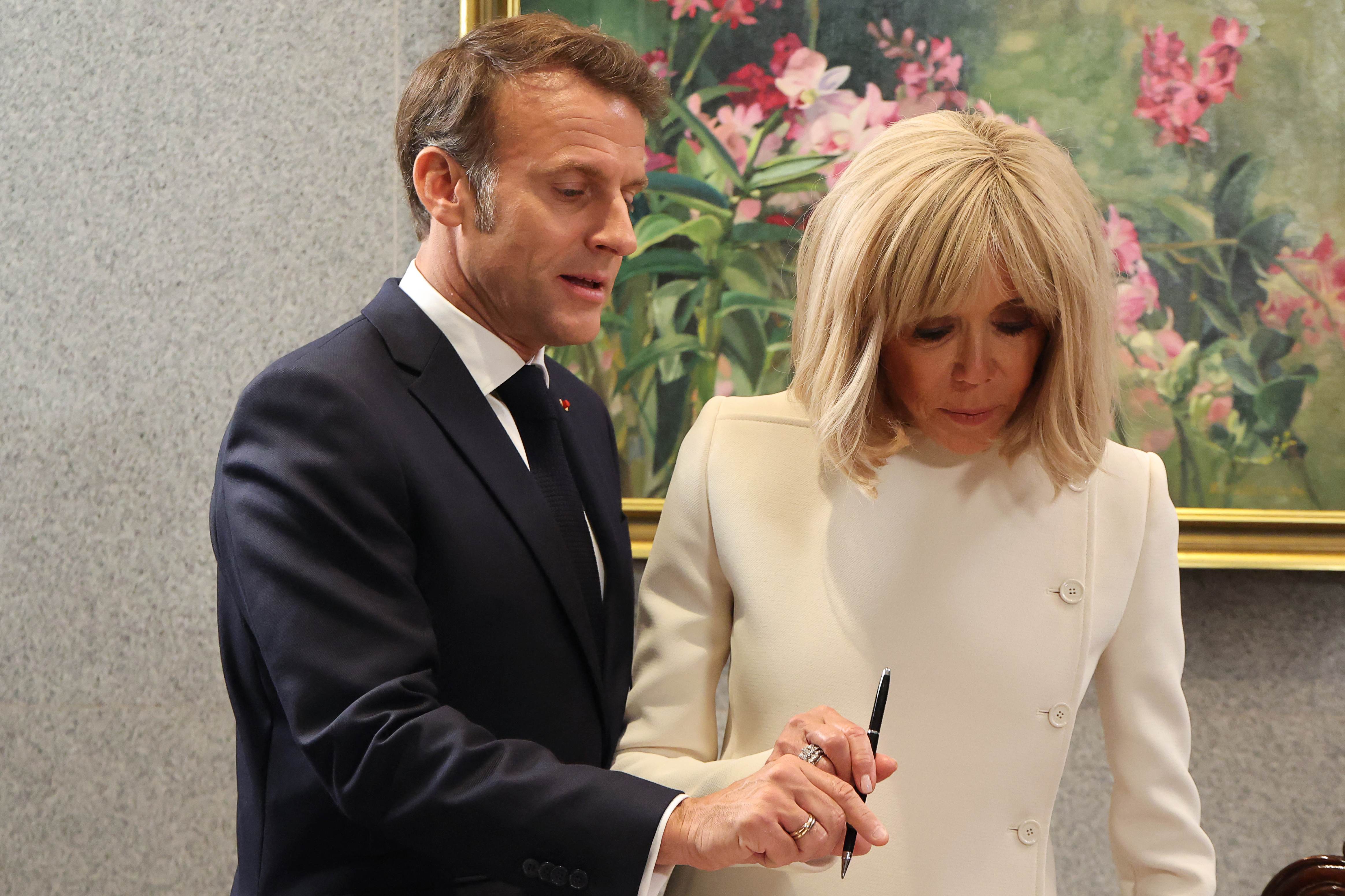 Au Parlement de Singapour, le 30 mai 2025, le président français se tenait aux côtés de Brigitte alors qu'ils s'apprêtaient à signer le livre d'or officiel.