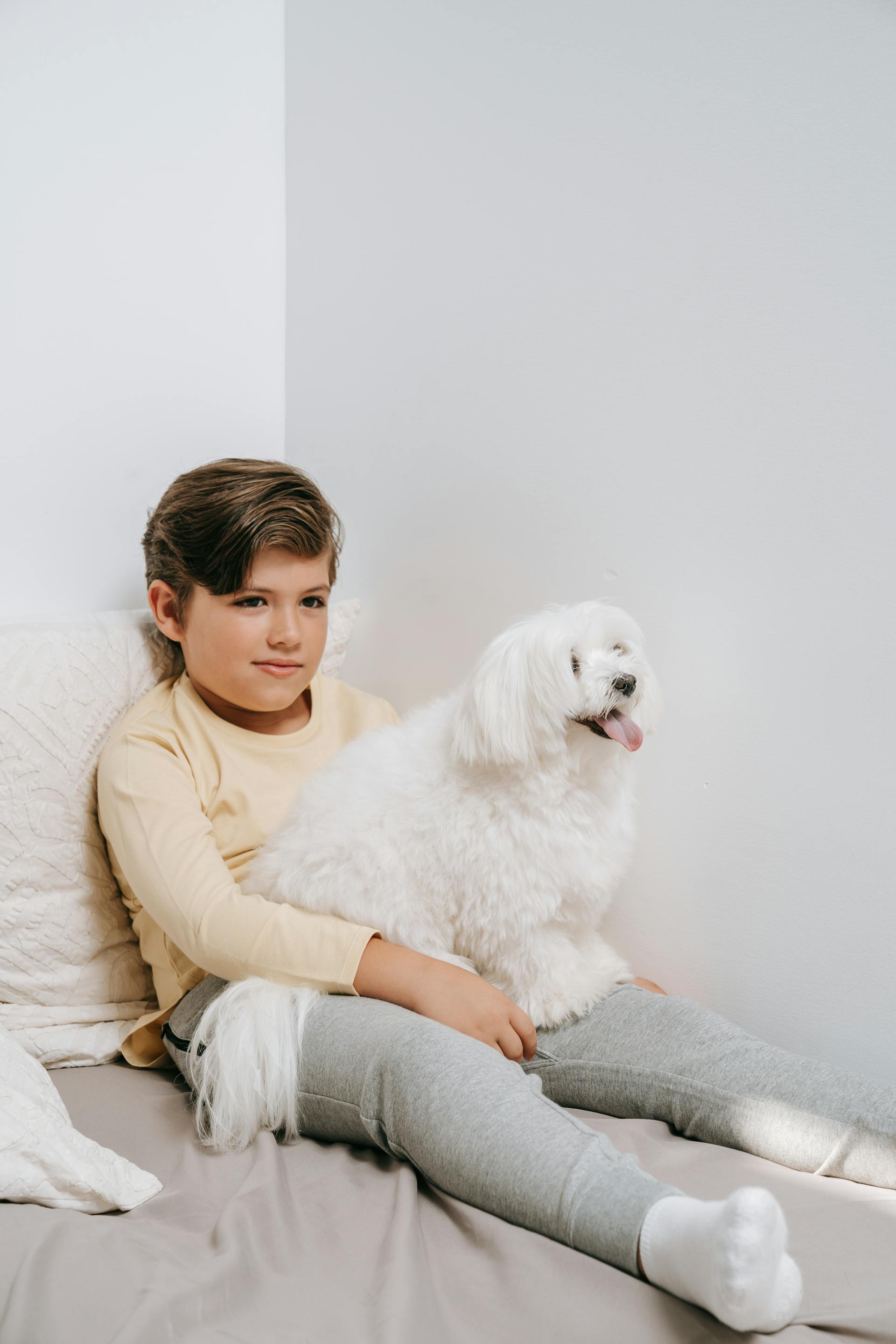 Un garçon sur un lit avec un chien | Source : Pexels