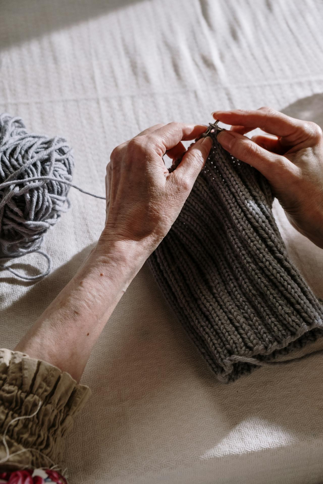Gros plan sur une femme âgée qui tricote un fil gris | Source : Pexels