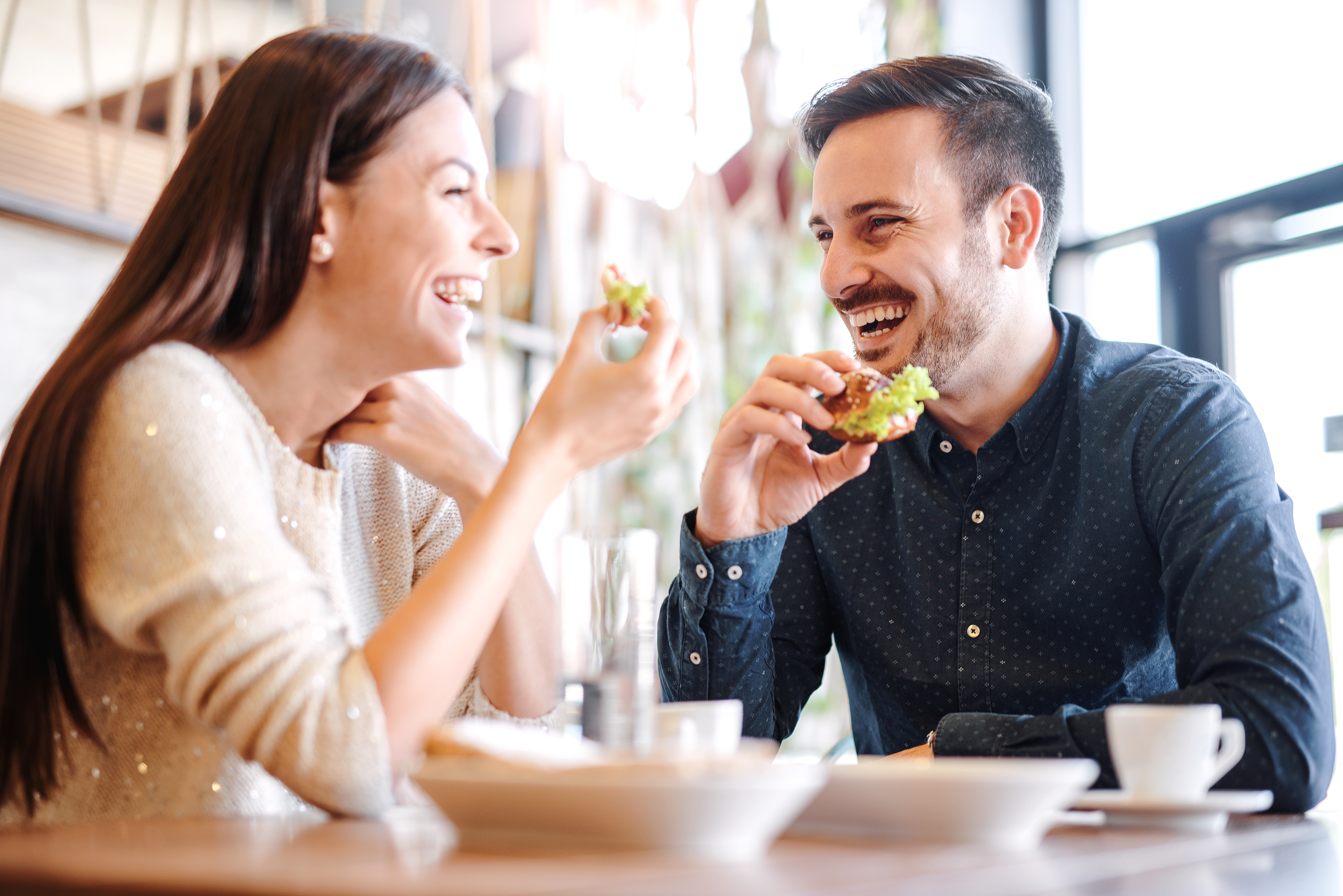 Un couple qui rit en prenant un repas ensemble | Source : Shutterstock
