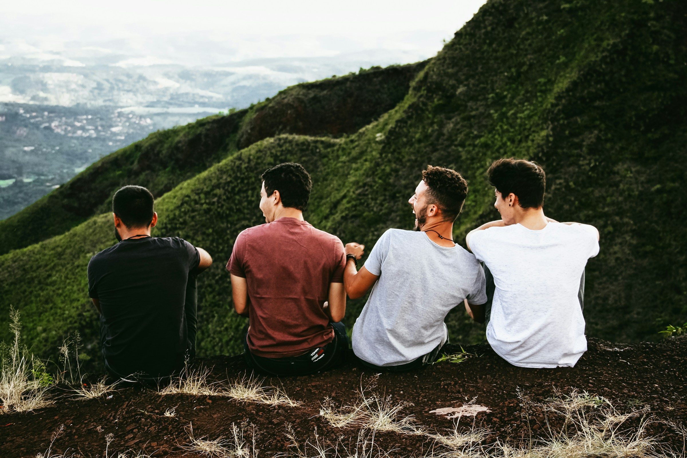 Quatre jeunes hommes assis sur un sentier de montagne | Source : Unsplash