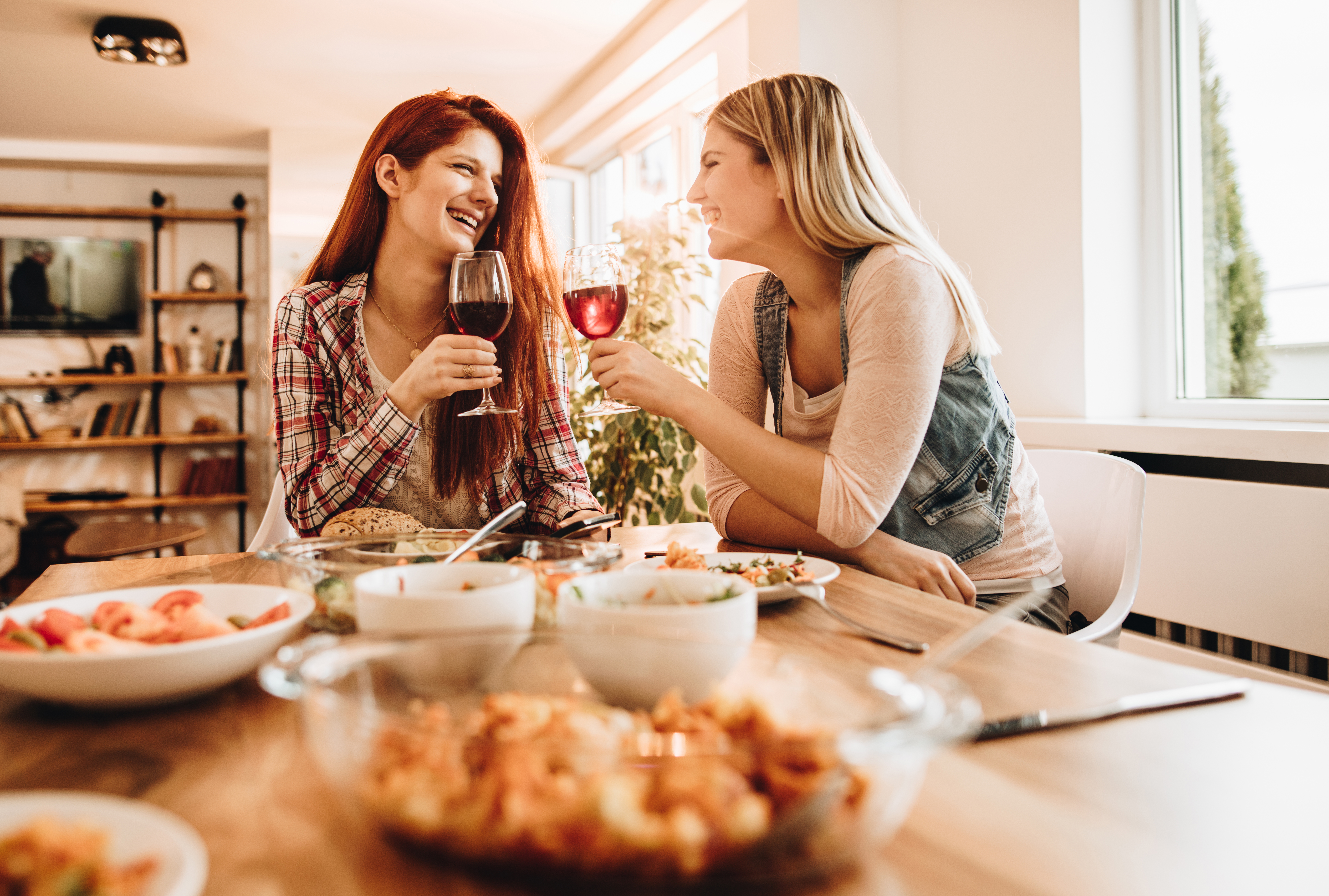 Jeunes femmes heureuses discutant et buvant du vin pendant le déjeuner | Source : Getty Images