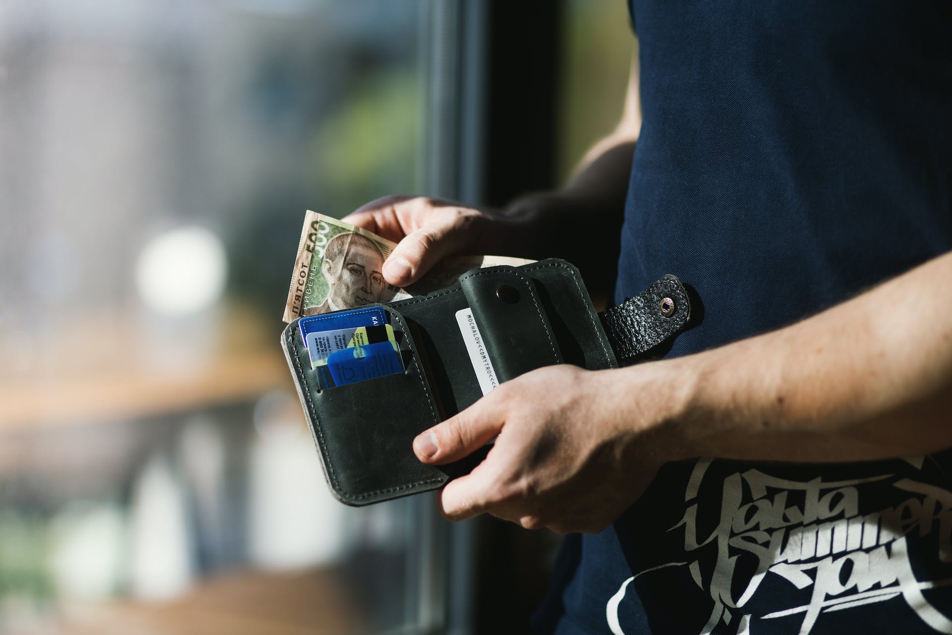 Une personne tenant un portefeuille en cuir noir avec de l'argent | Source : Pexels