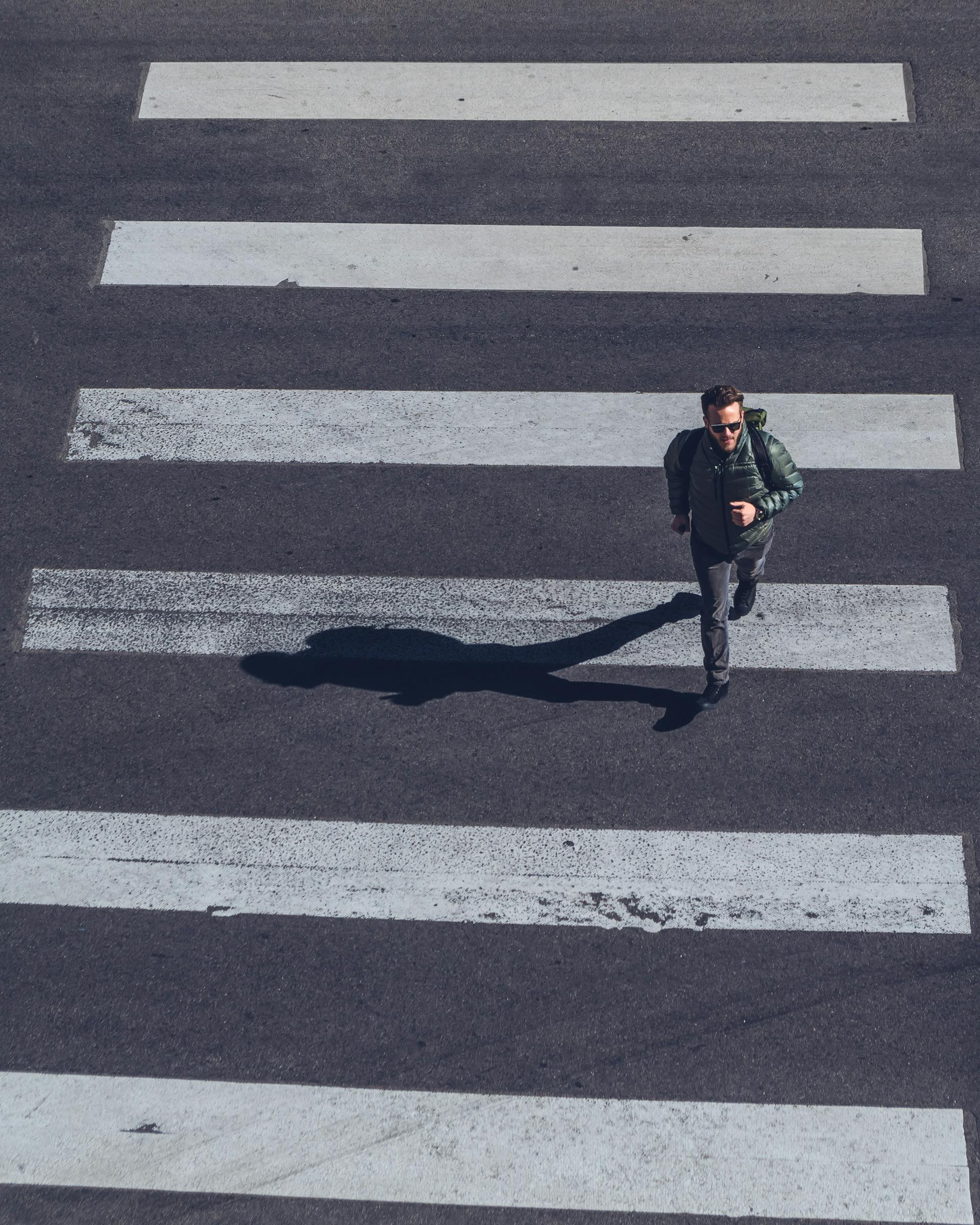 Un homme qui se dépêche de franchir un passage pour piétons | Source : Pexels