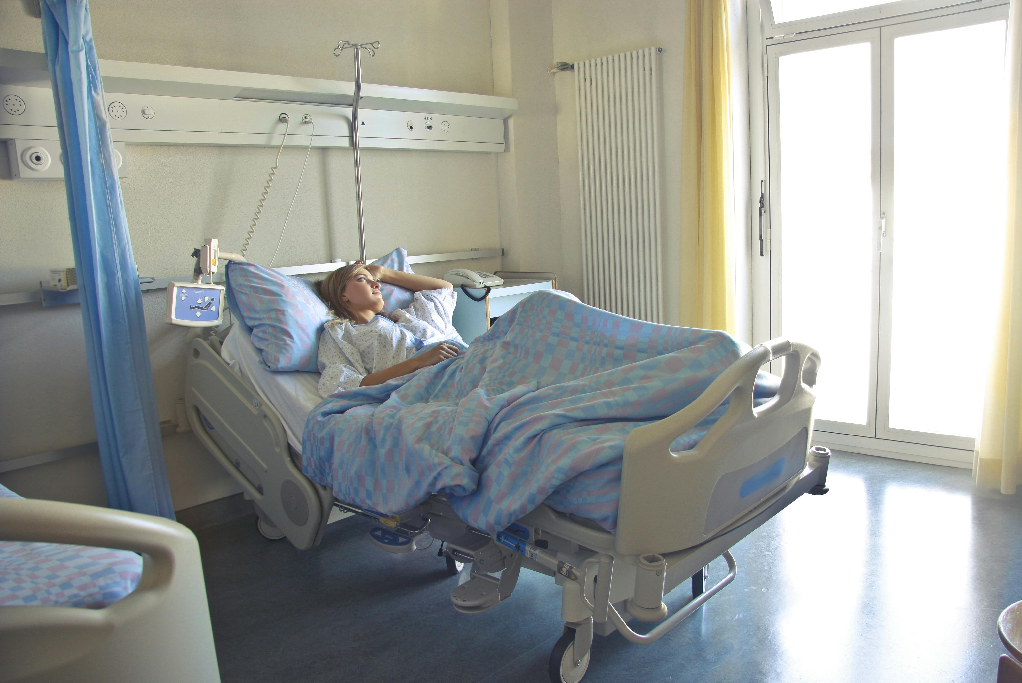 Une femme qui regarde dehors alors qu'elle est allongée dans un lit d'hôpital | Source : Pexels