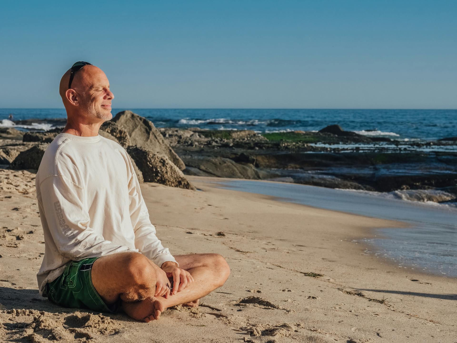 Un homme sourit en faisant du yoga sur la plage | Source : Pexels