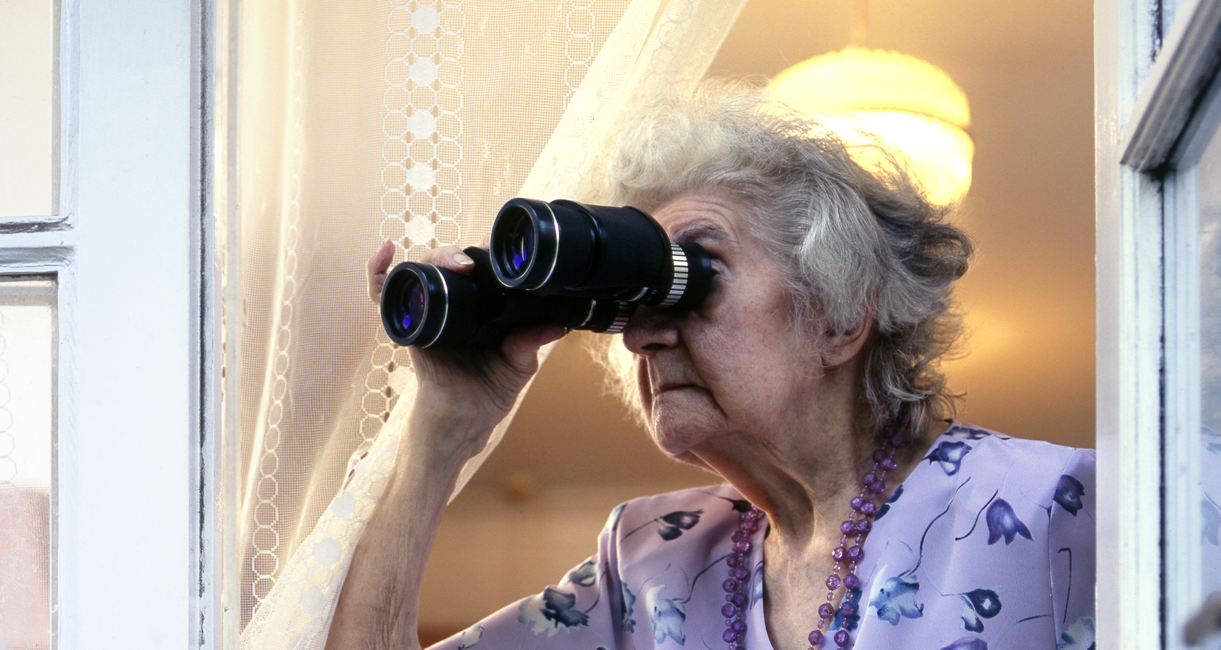 Femme âgée regardant à travers des jumelles | Source : Getty Images