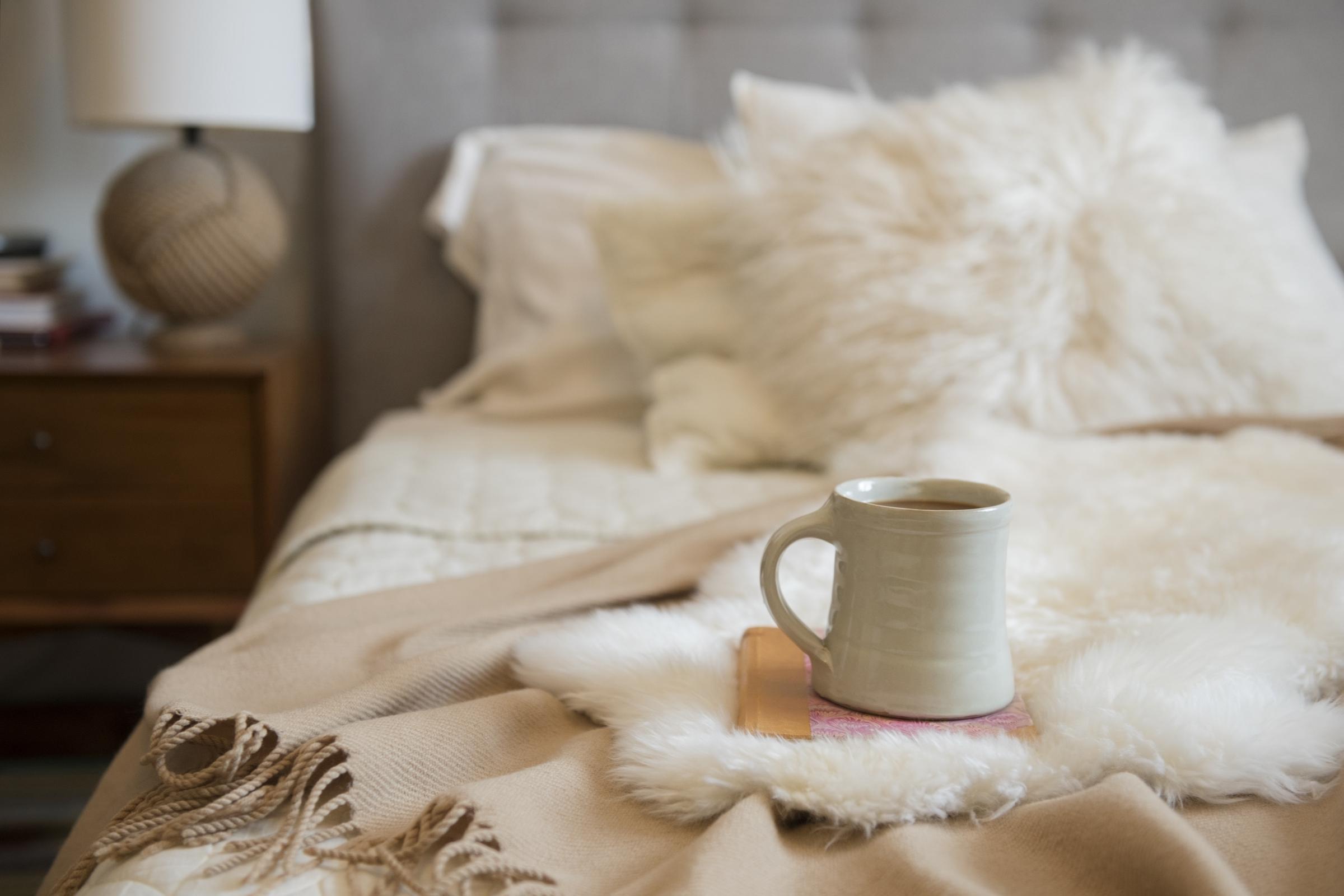 Une tasse de café placée au-dessus d'un livre sur un lit | Source : Getty Images