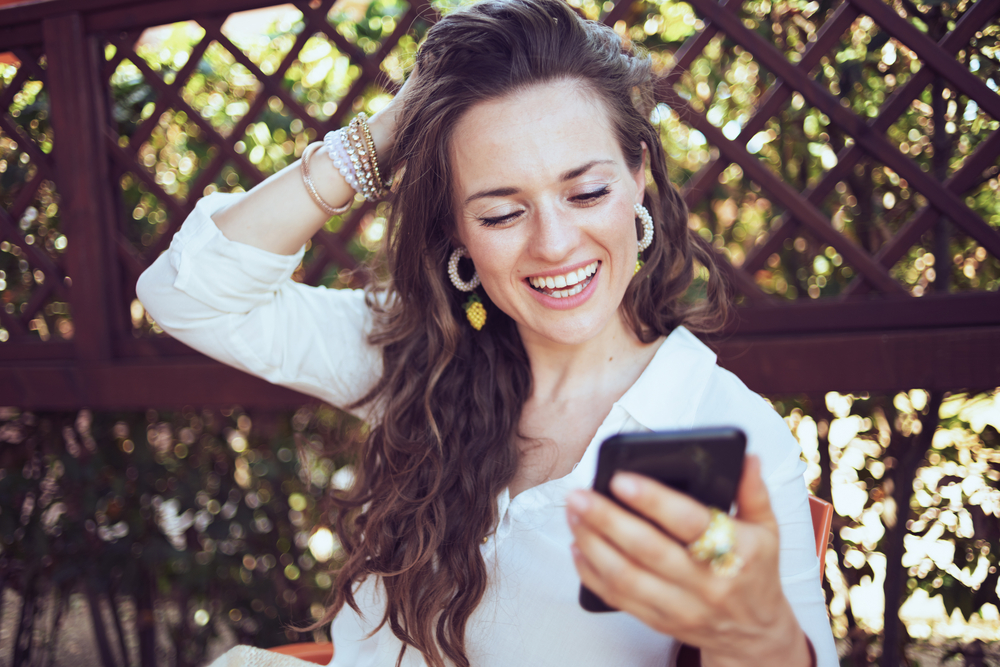 Une femme qui sourit tout en utilisant son téléphone | Source : Shutterstock