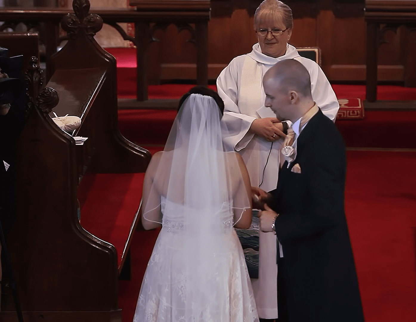 Liz and Ollie standing at the altar on their wedding day. │Source: youtube.com/Van Rensburg Films