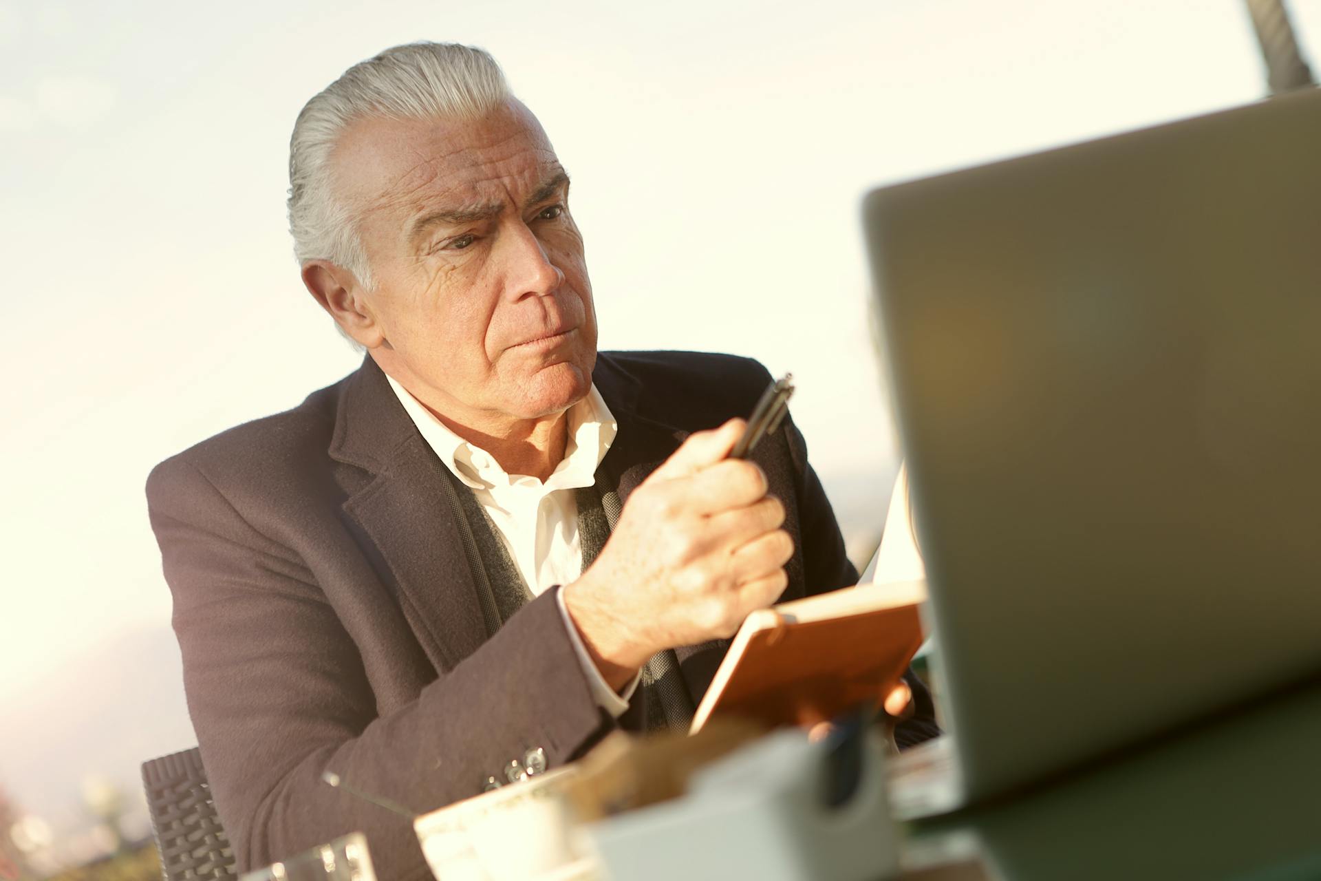 Un homme âgé et sévère assis devant son ordinateur portable dans son bureau | Source : Pexels