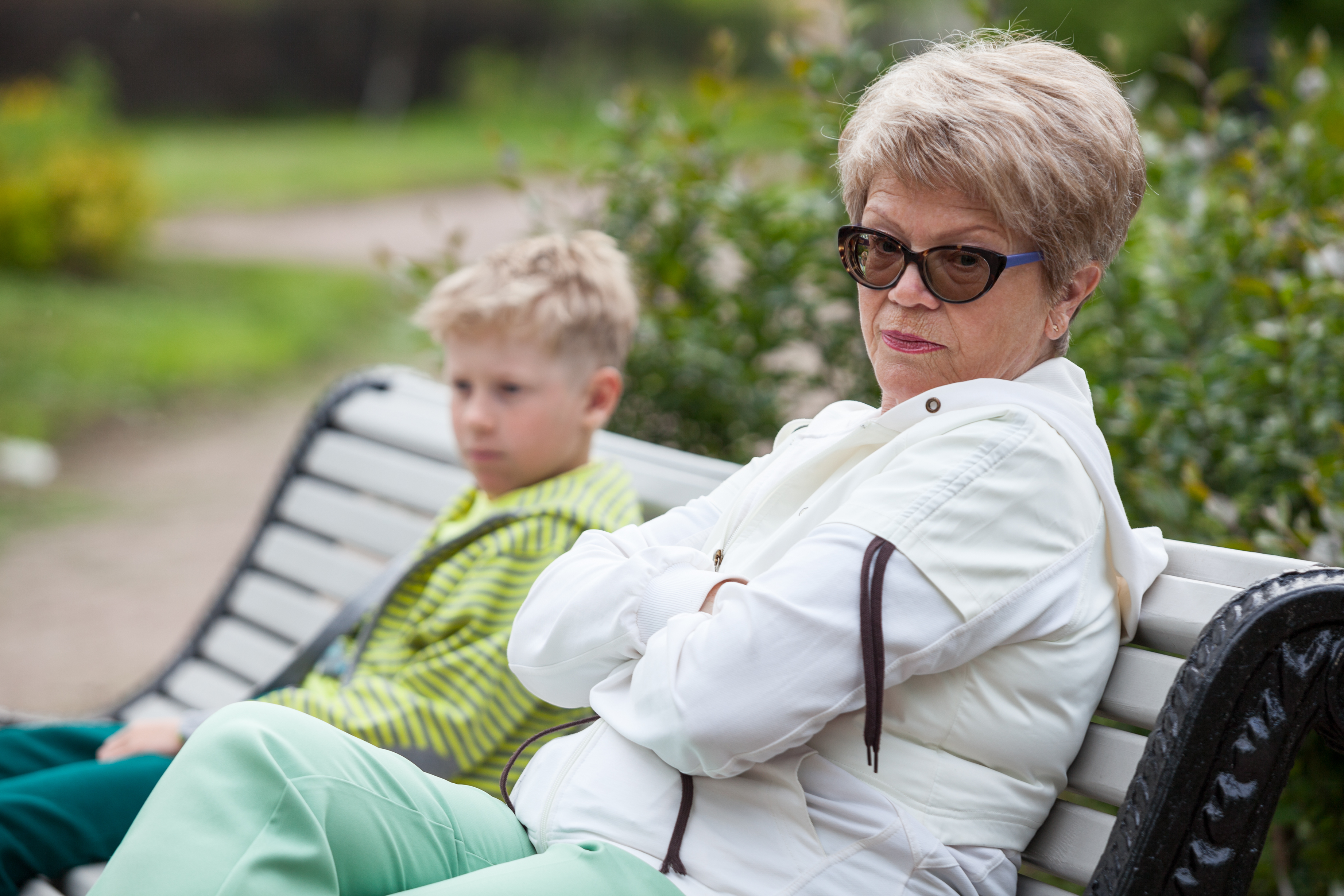 Une femme plus âgée ignore un jeune garçon sur un banc | Source : Shutterstock