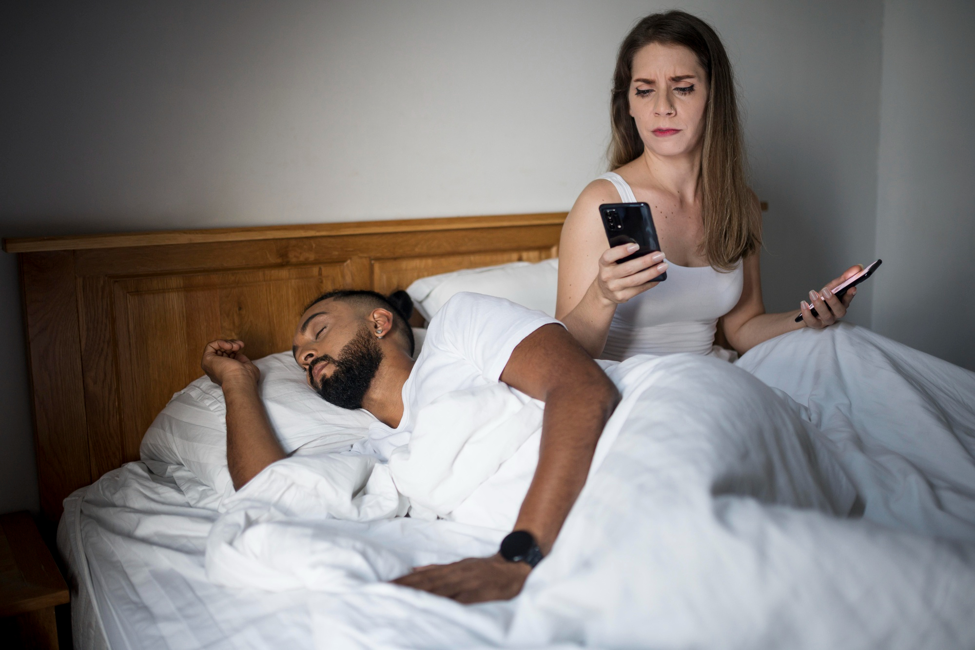 Une femme qui fouille dans le téléphone d'un homme pendant qu'il dort | Source : Freepik