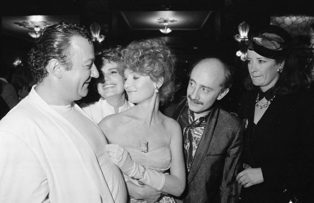 Isabelle Huppert et Miou-Miou entourées de Coluche, Michel Blanc et Dominique Lavanant lors d'une première le 5 avril 1983 à Paris, France. | Photo : Getty Images