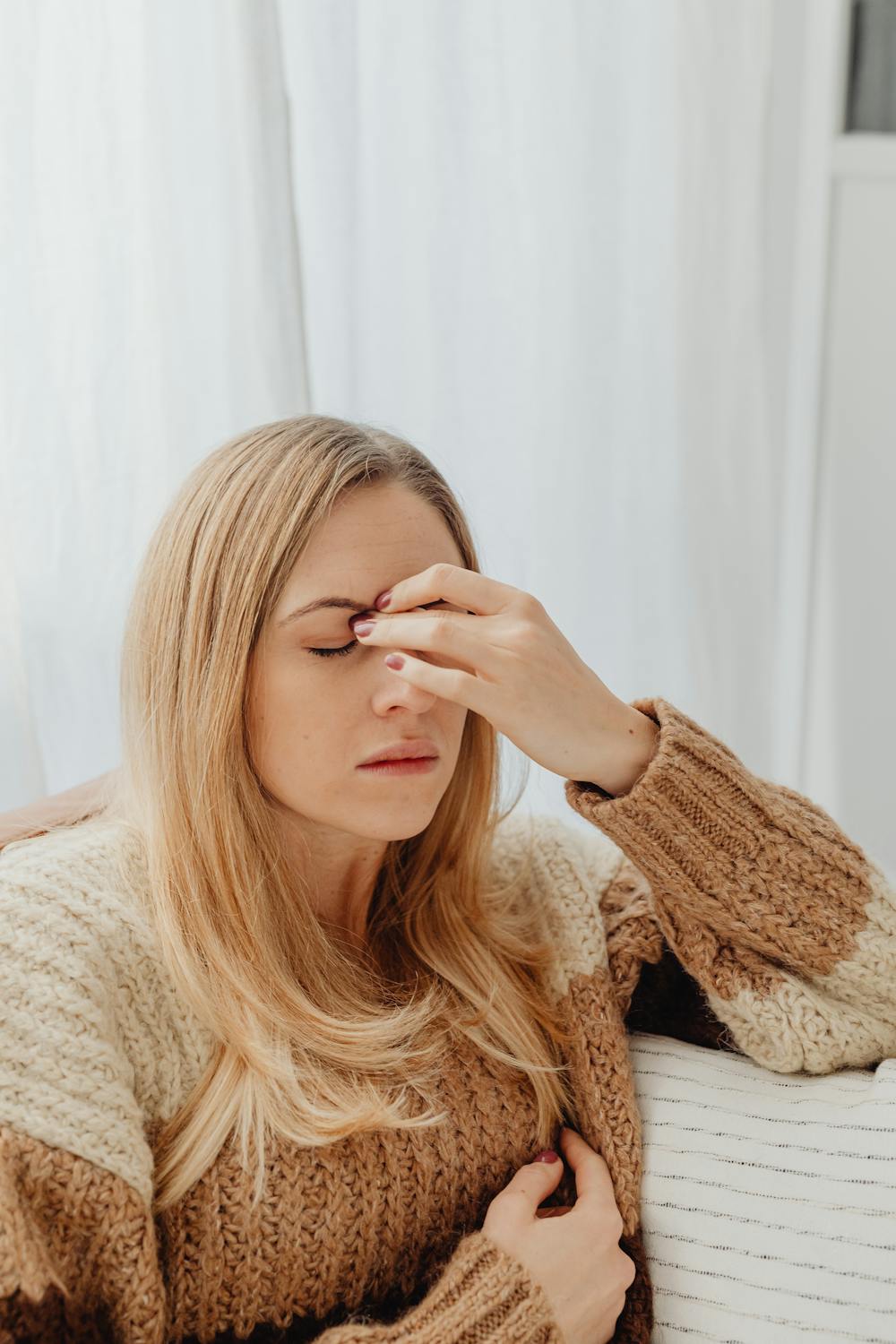 Une femme renfrognée qui se frotte les sourcils ⏐ Source : Pexels