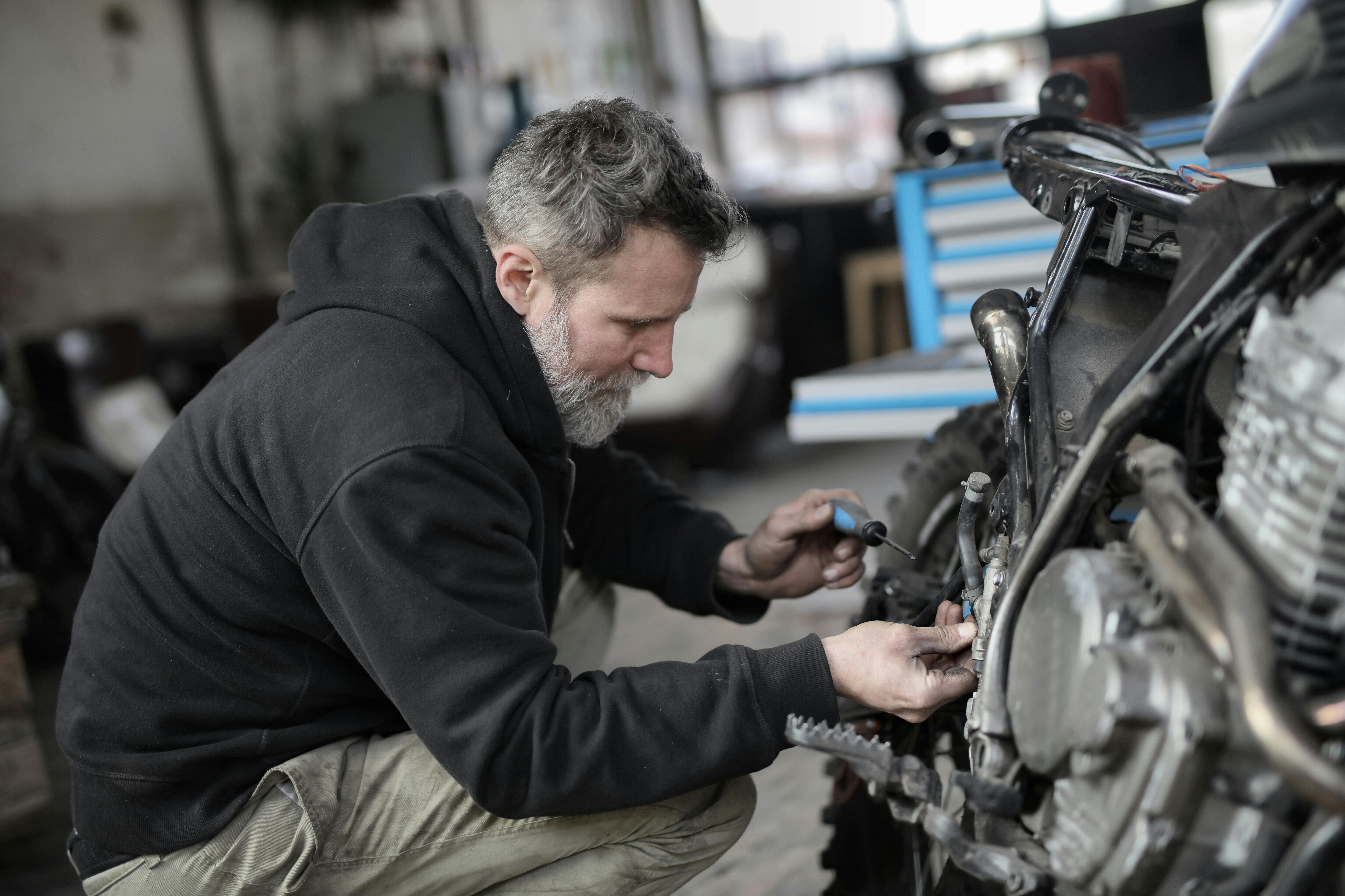 Un homme en train de réparer une moto | Source : Pexels