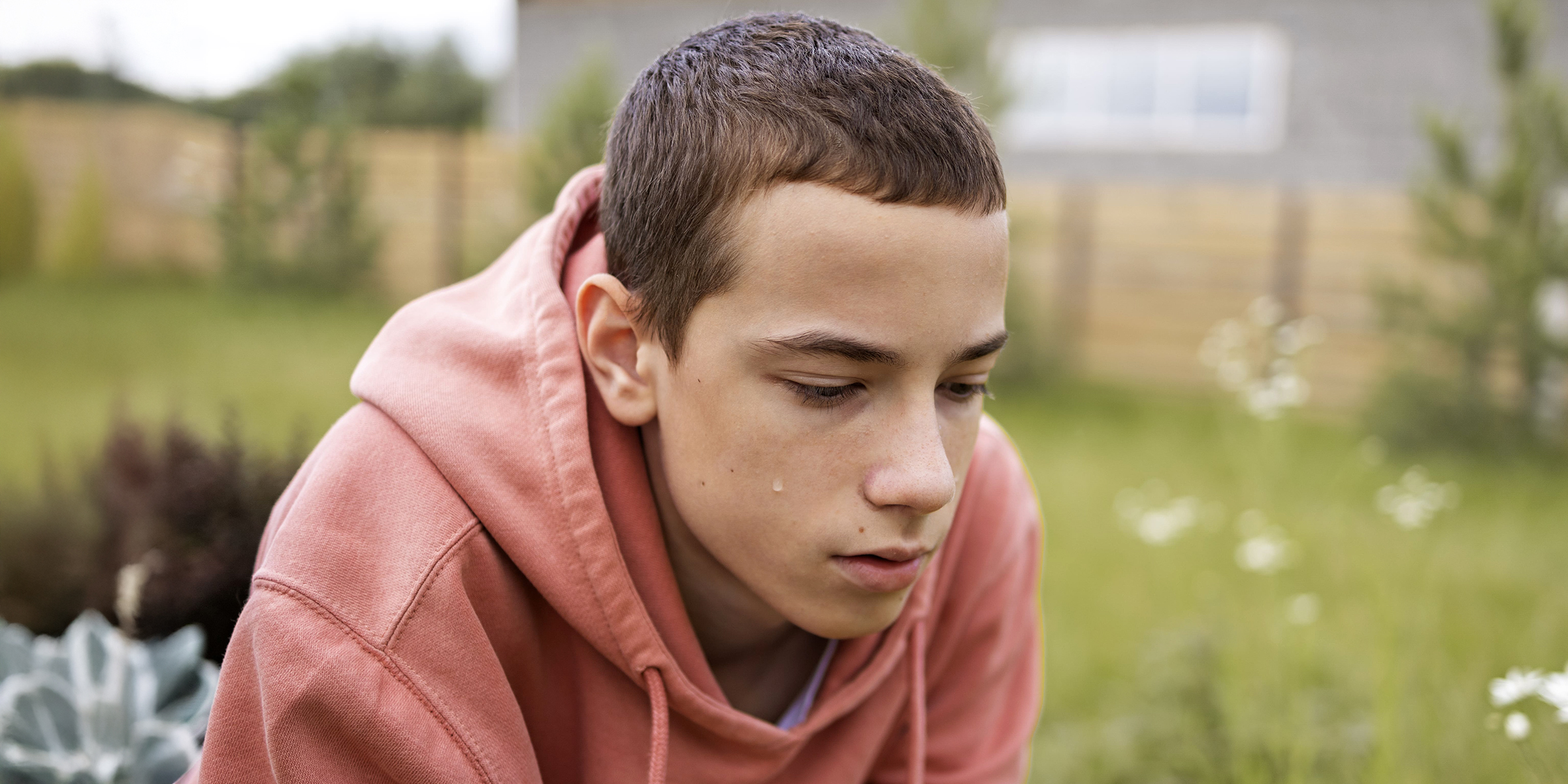 Un adolescent déprimé assis à l'extérieur, le visage abattu | Source : Freepik