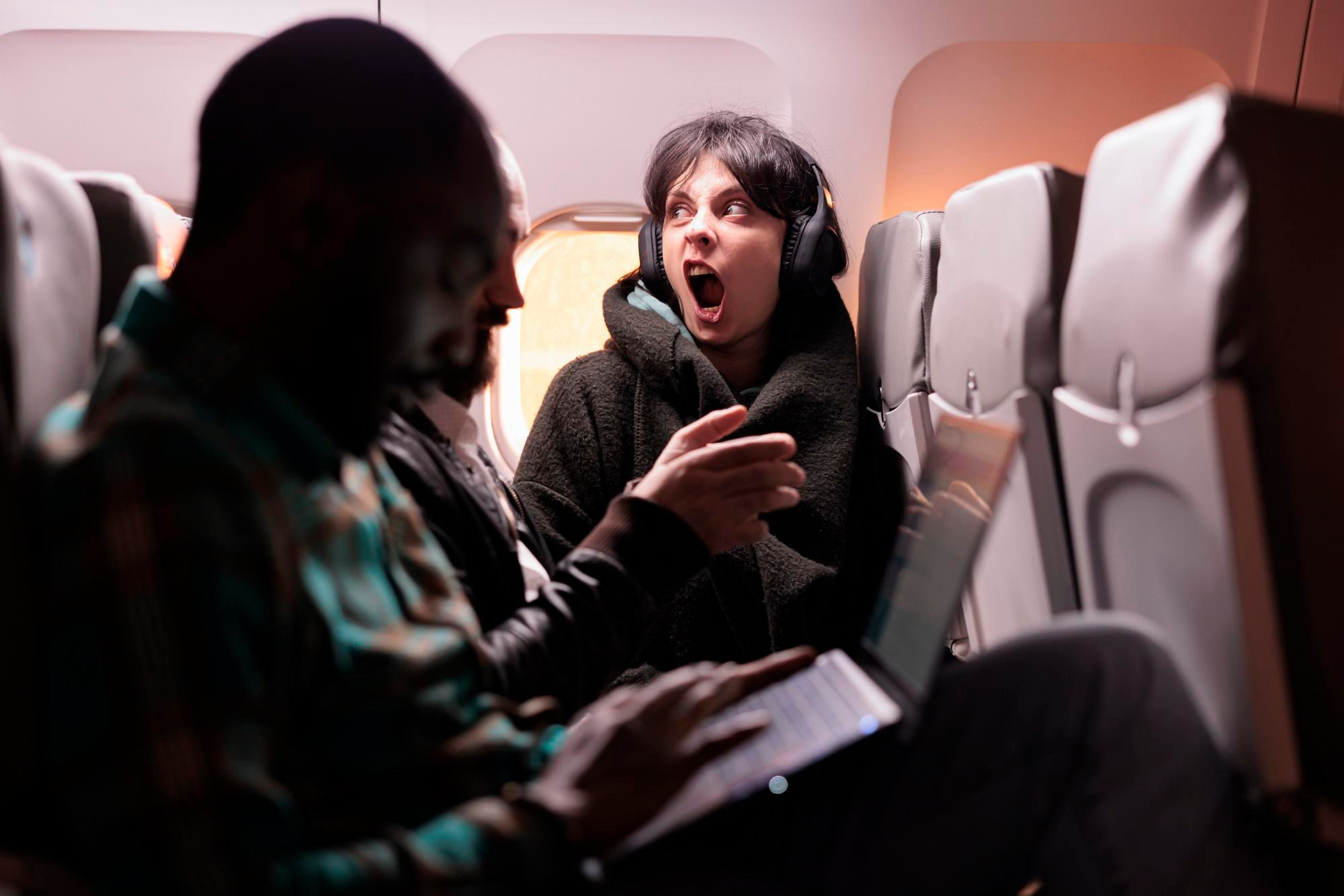 Une femme bouleversée porte un casque d'écoute tout en criant sur un vol | Source : Freepik