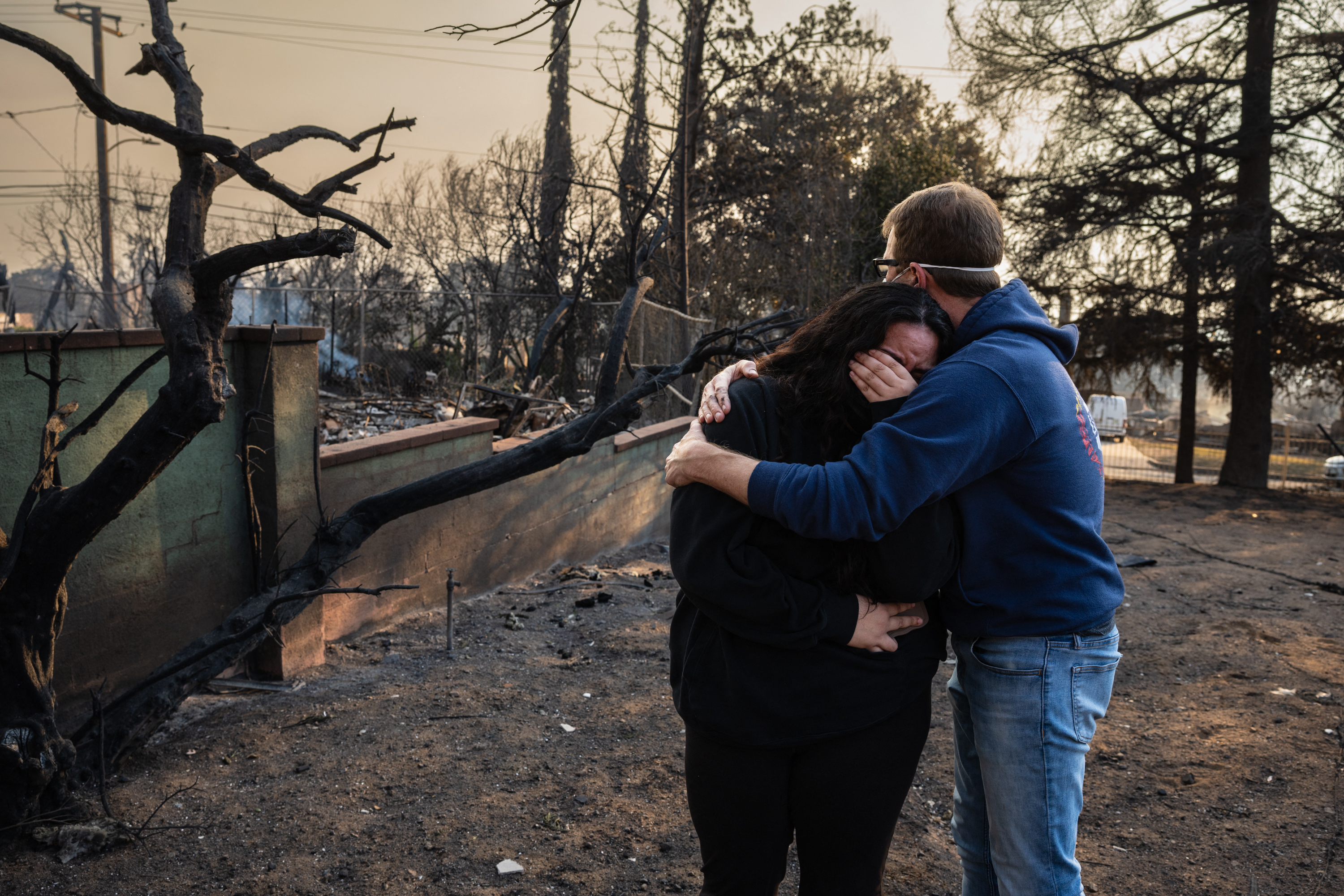 Un homme embrasse sa fille sur les ruines calcinées de leur maison familiale brûlée dans l'incendie Eaton, le 9 janvier 2025, à Altadena, en Californie. | Source : Getty Images