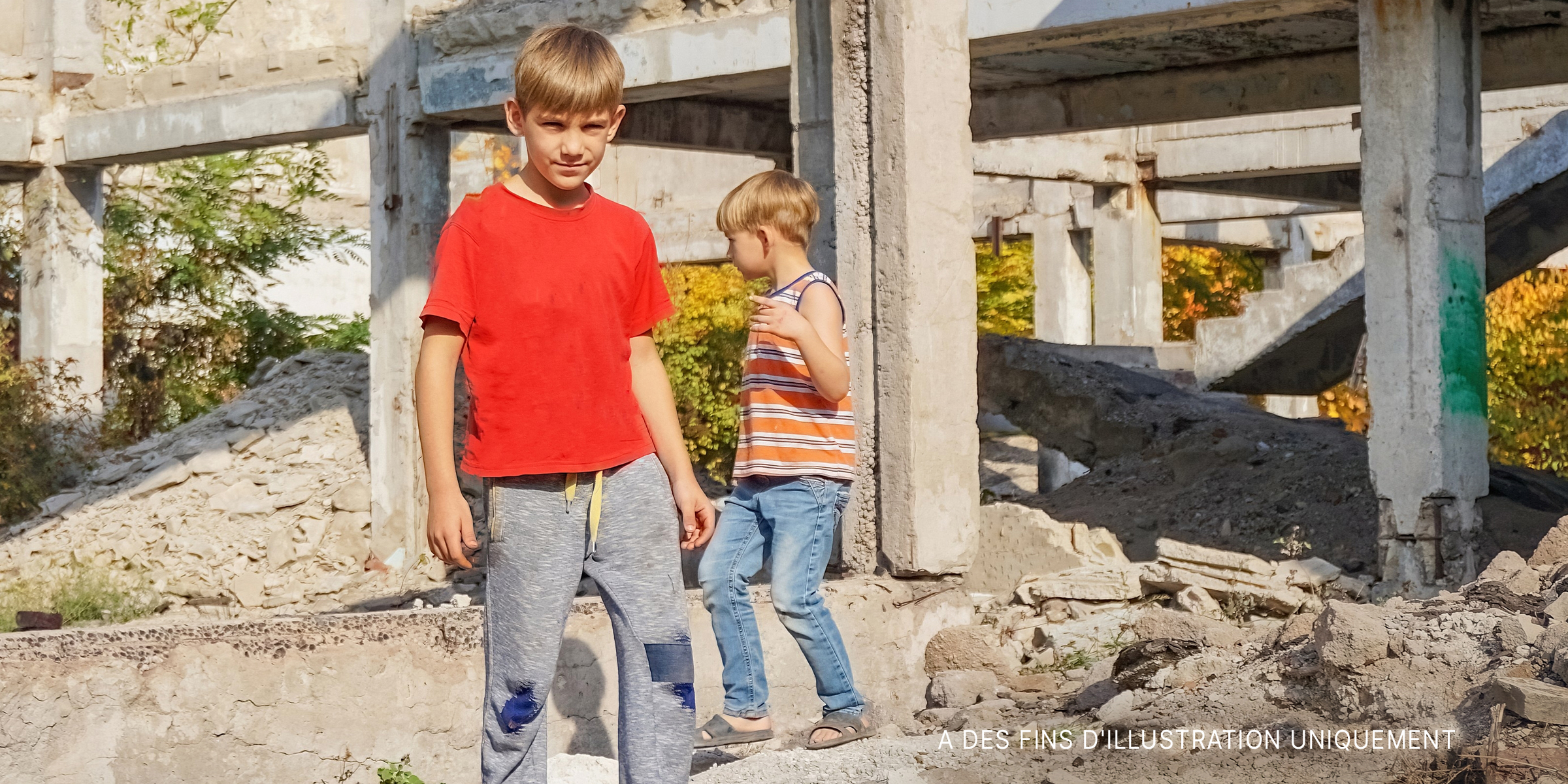 Deux jeunes garçons debout près de vieux piliers en béton | Source : Shutterstock