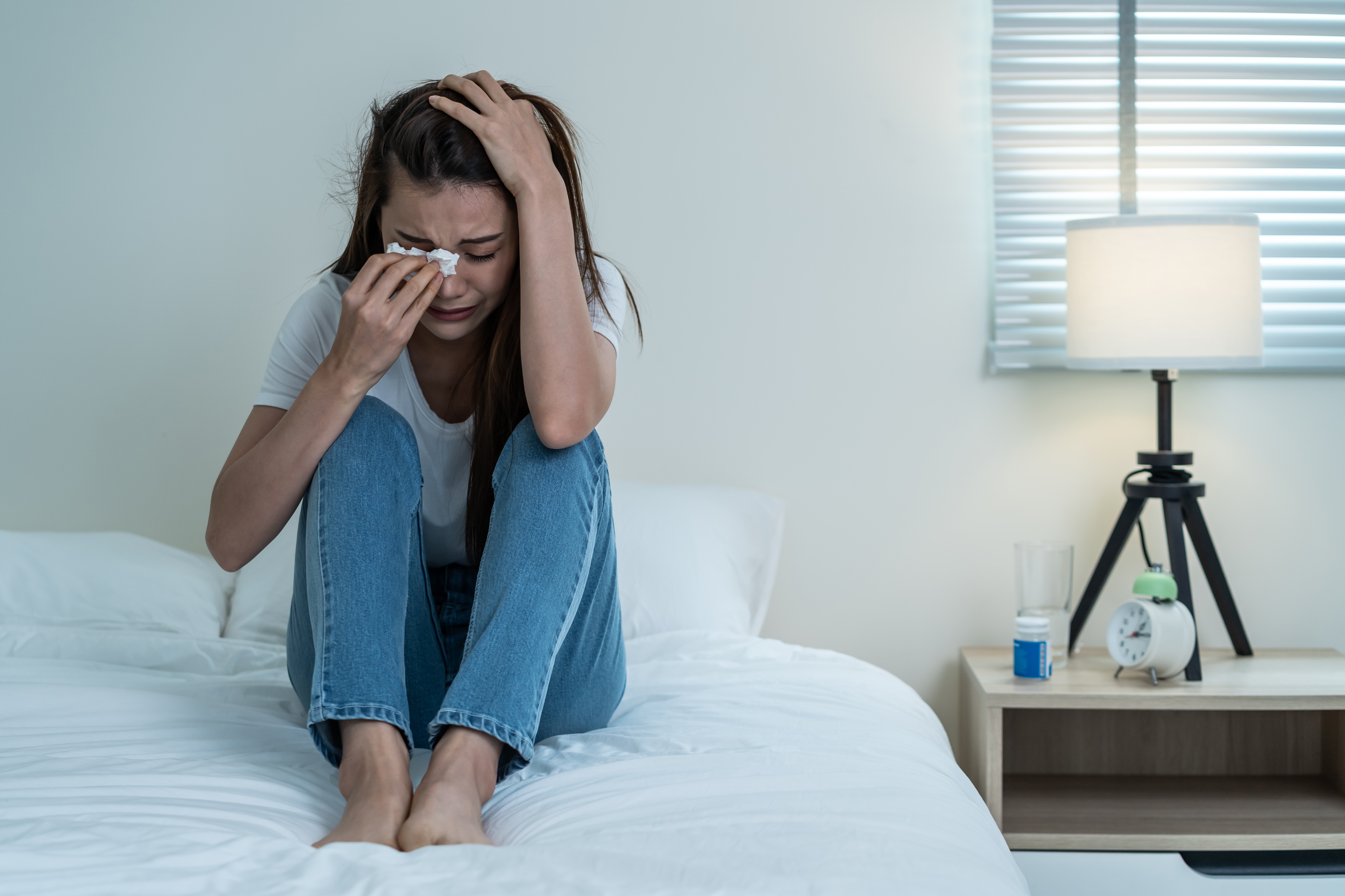 Une femme qui pleure sur un lit | Source : Shutterstock