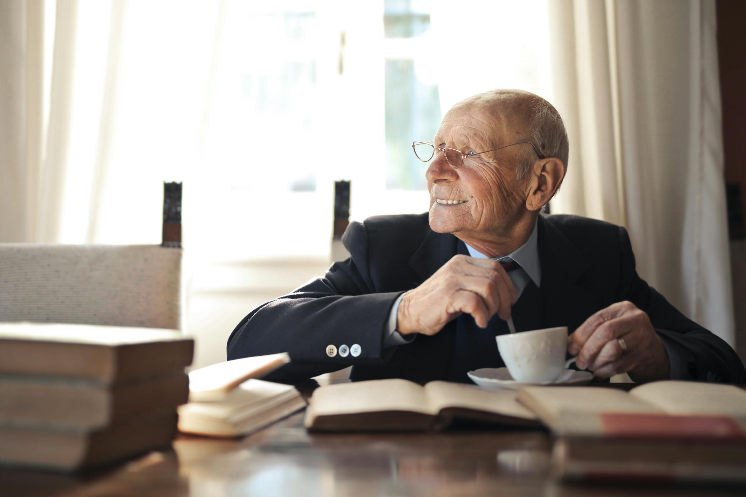 Un homme assis à un bureau, souriant, avec des livres sur la table | Source : Pexels