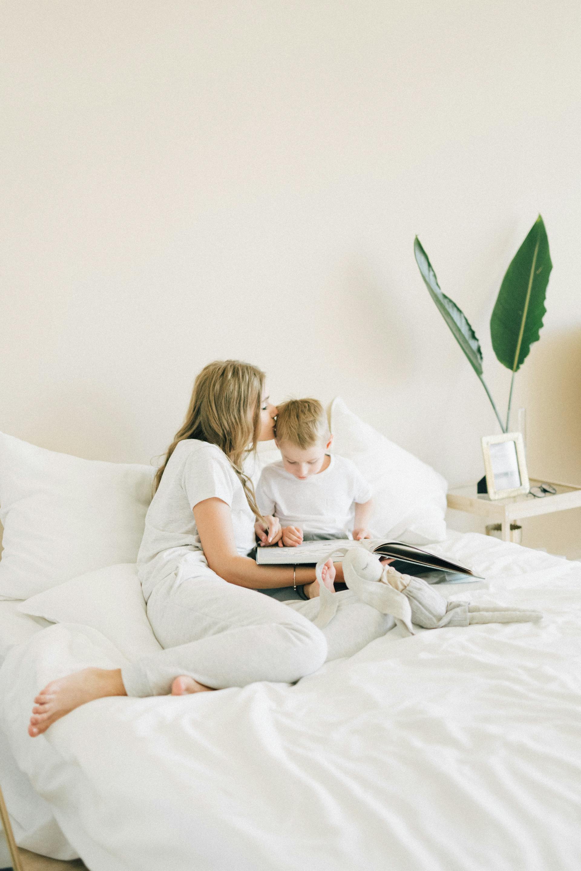 Une femme bordant son fils dans son lit | Source : Pexels