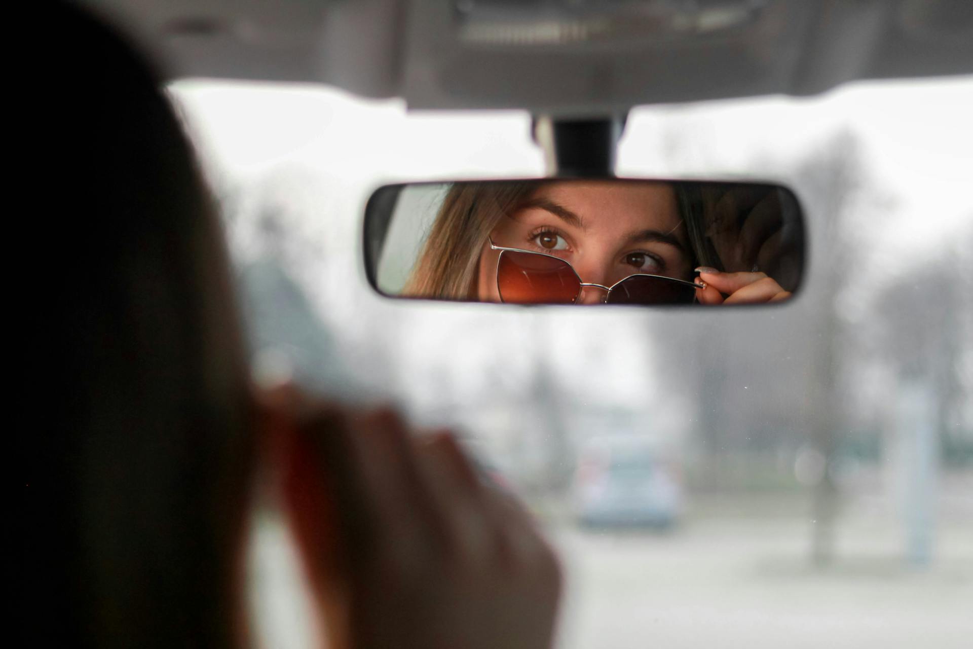 Femme confiante portant des lunettes de soleil et regardant son reflet dans le rétroviseur | Source : Pexels