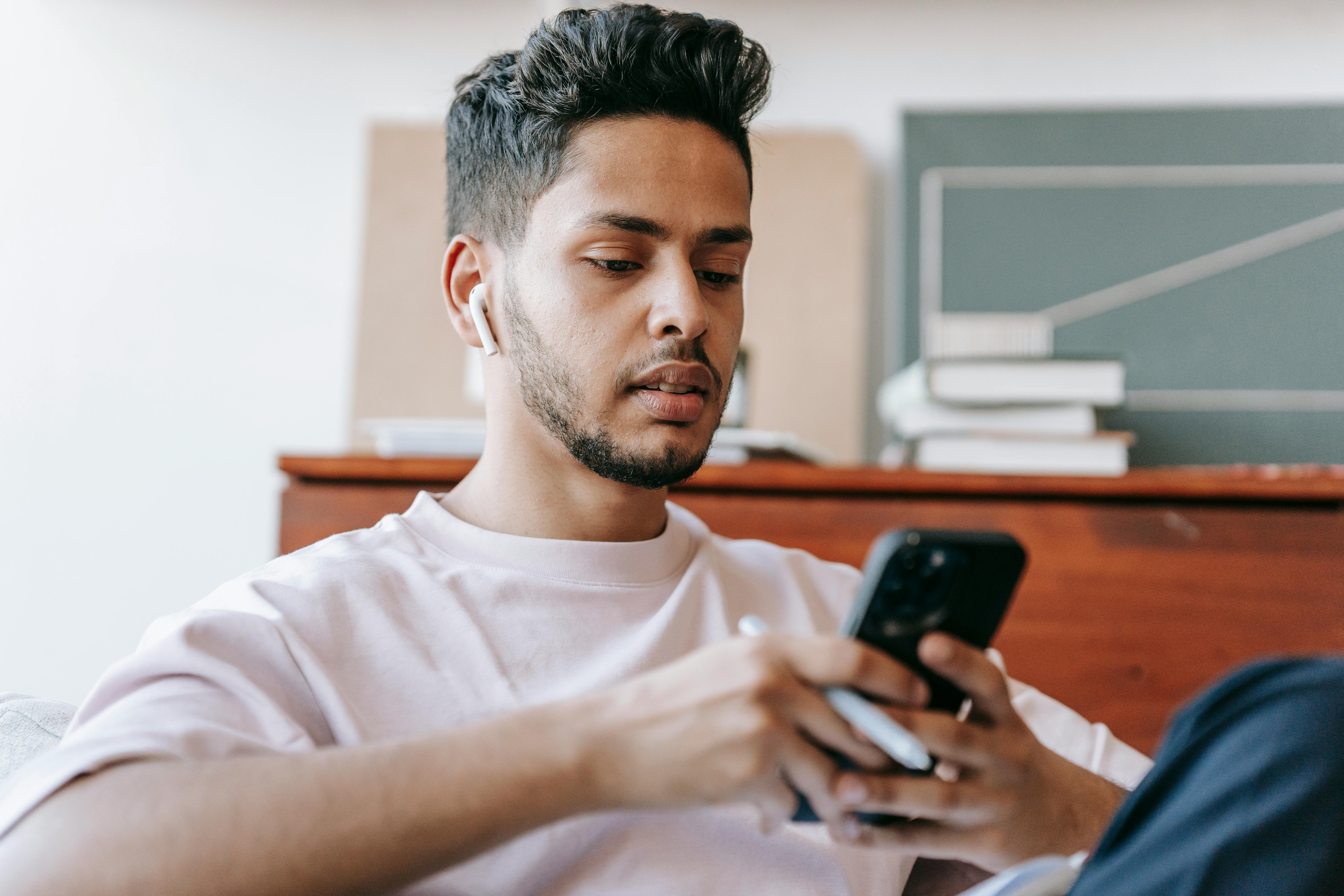 Un jeune homme utilisant son smartphone | Source : Pexels