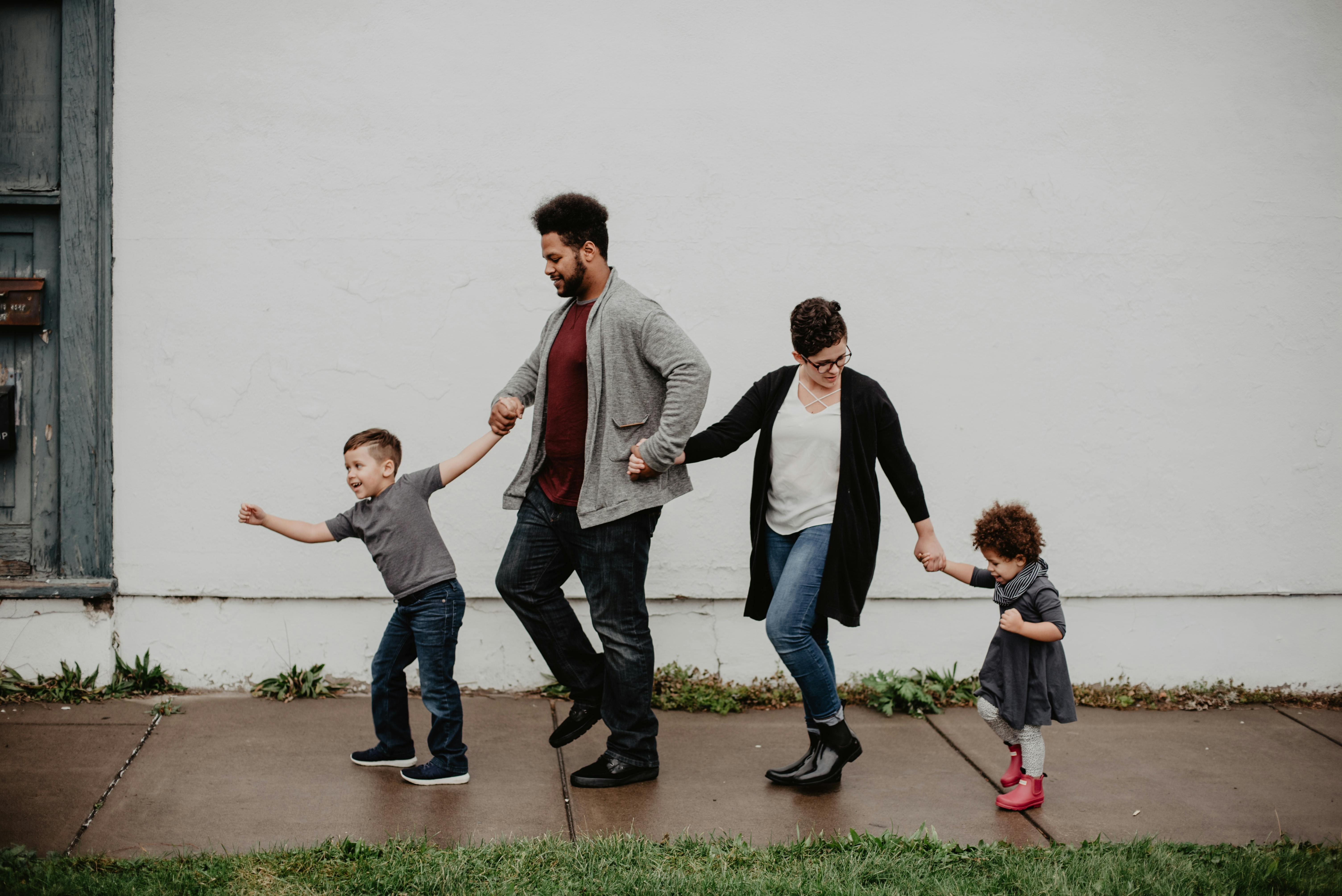 Une famille de quatre personnes se tenant par la main et marchant | Source : Pexels