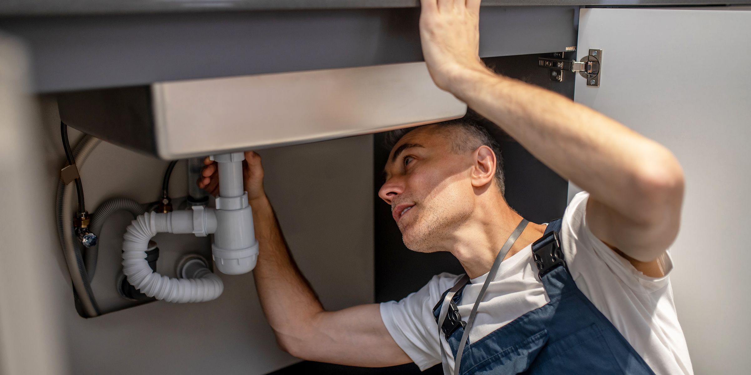 Un homme en train de réparer un évier de cuisine | Source : Shutterstock