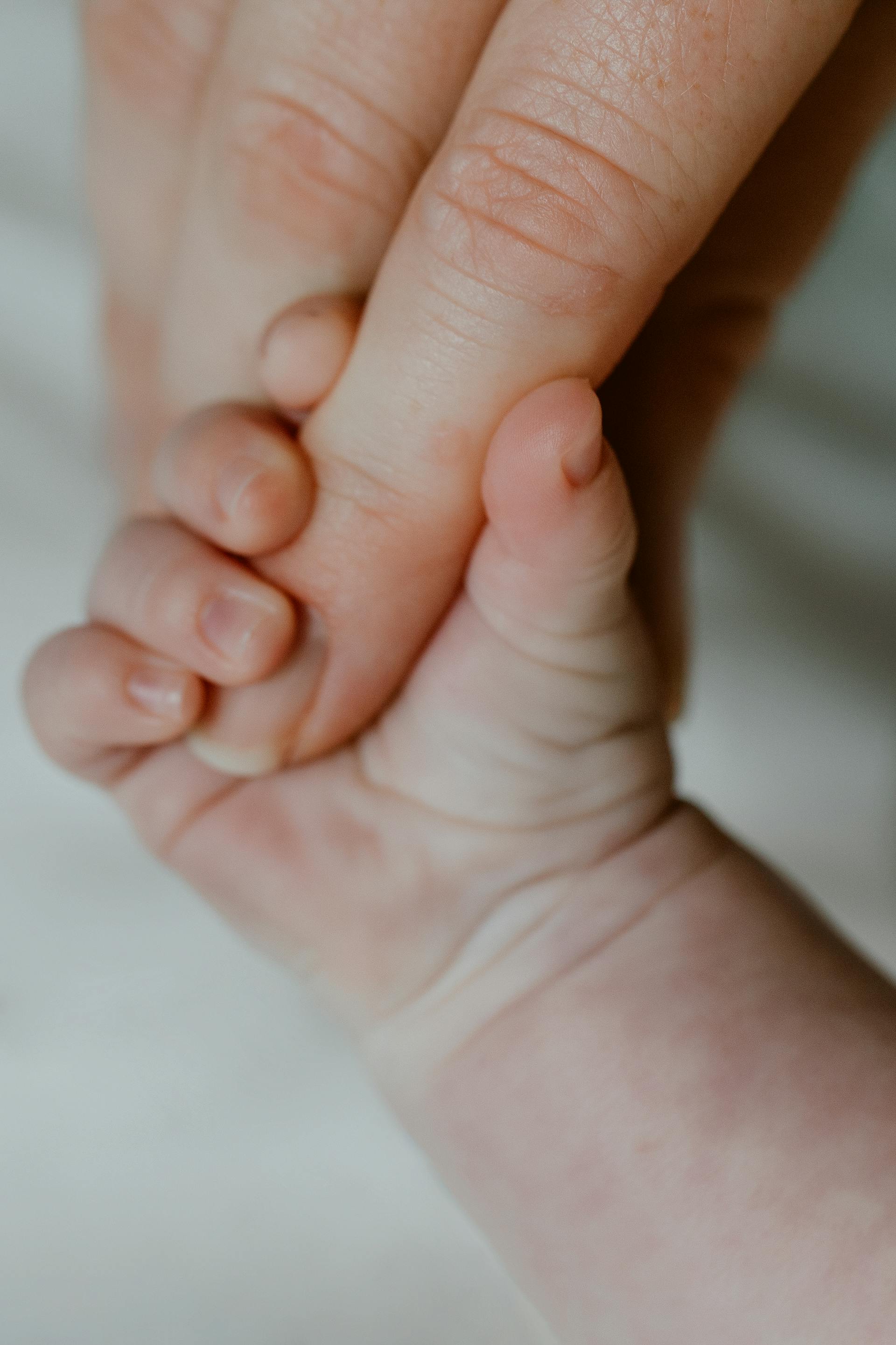 Un bébé tenant le doigt de sa mère | Source : Pexels