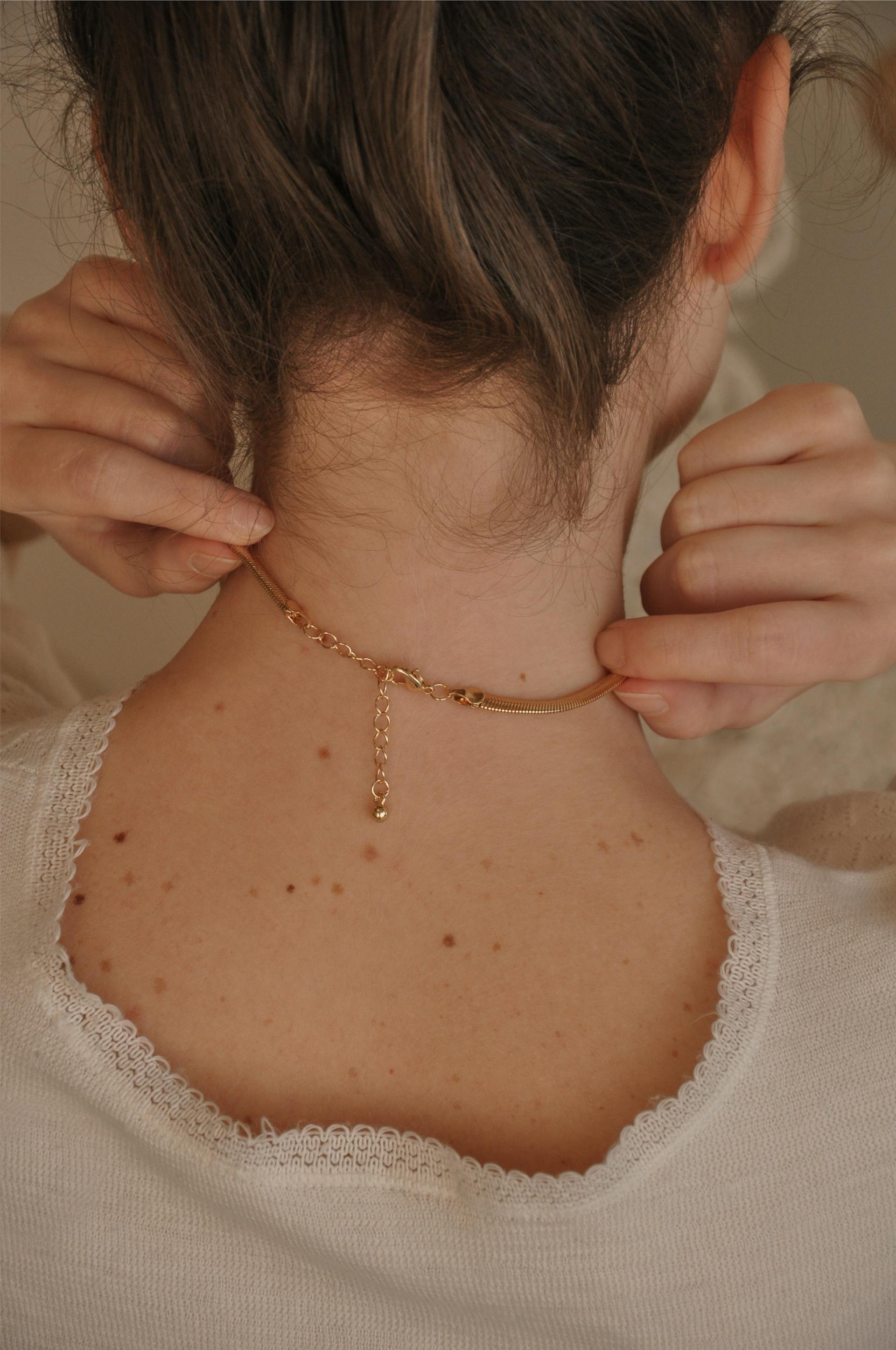 Vue de dos d'une femme touchant son collier | Source : Pexels