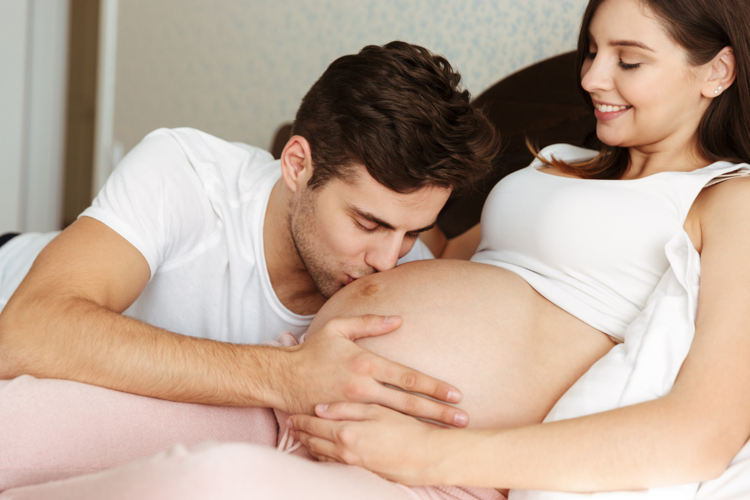 Un homme embrassant le baby bump de sa partenaire enceinte | Source : Freepik