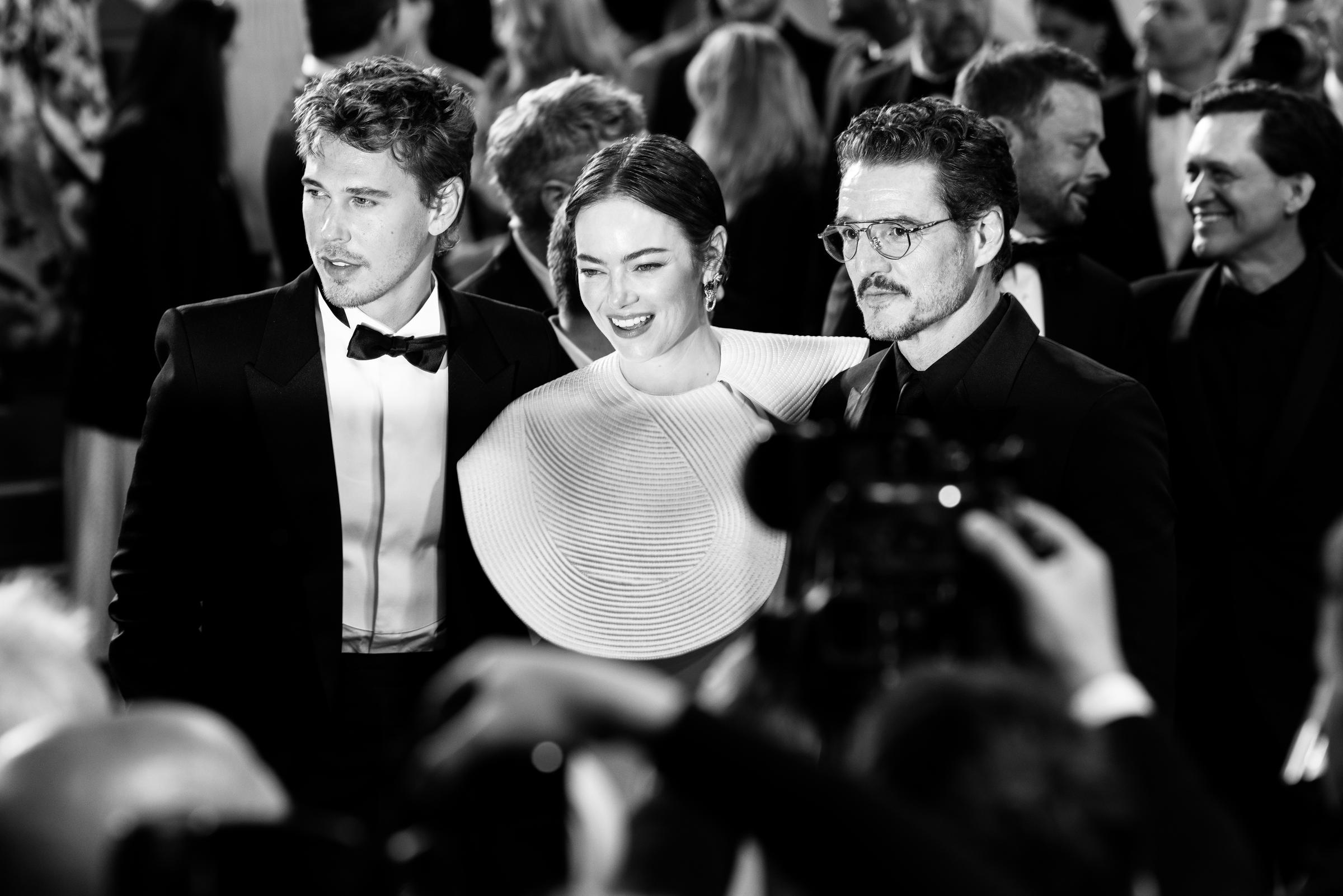 Austin Butler, Emma Stone et Pedro Pascal posent pour les photographes lors de la première du film "Eddington", capturé ici dans un moment saisissant en noir et blanc. Le trio respire le glamour moderne - Emma Stone dans une robe blanche sculpturale, flanquée de ses coéquipiers en smoking classique.