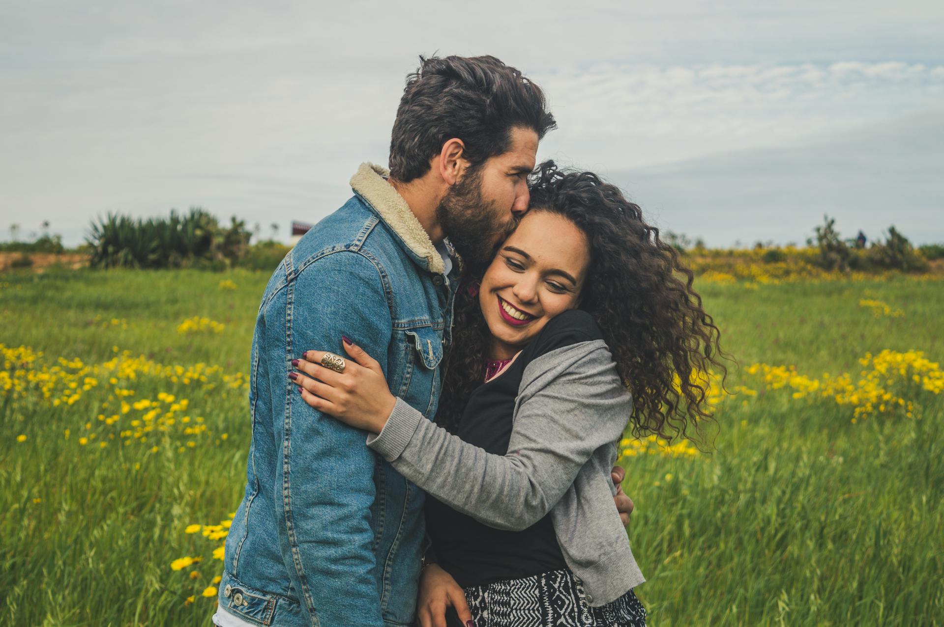 Un jeune couple souriant dans un champ | Source : Pexels