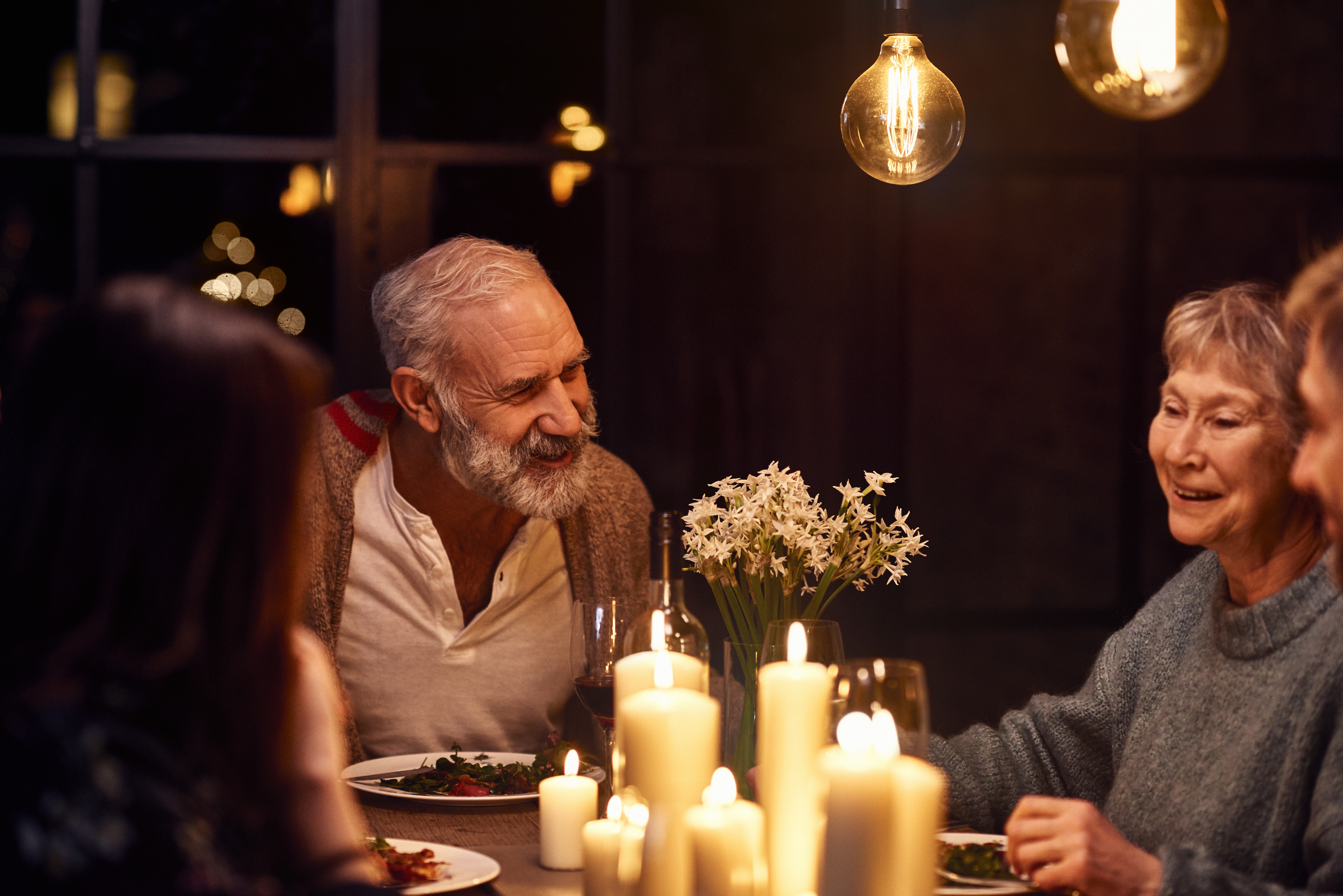 Homme mûr discutant lors d'un dîner et souriant avec sa famille | Source : Getty Images
