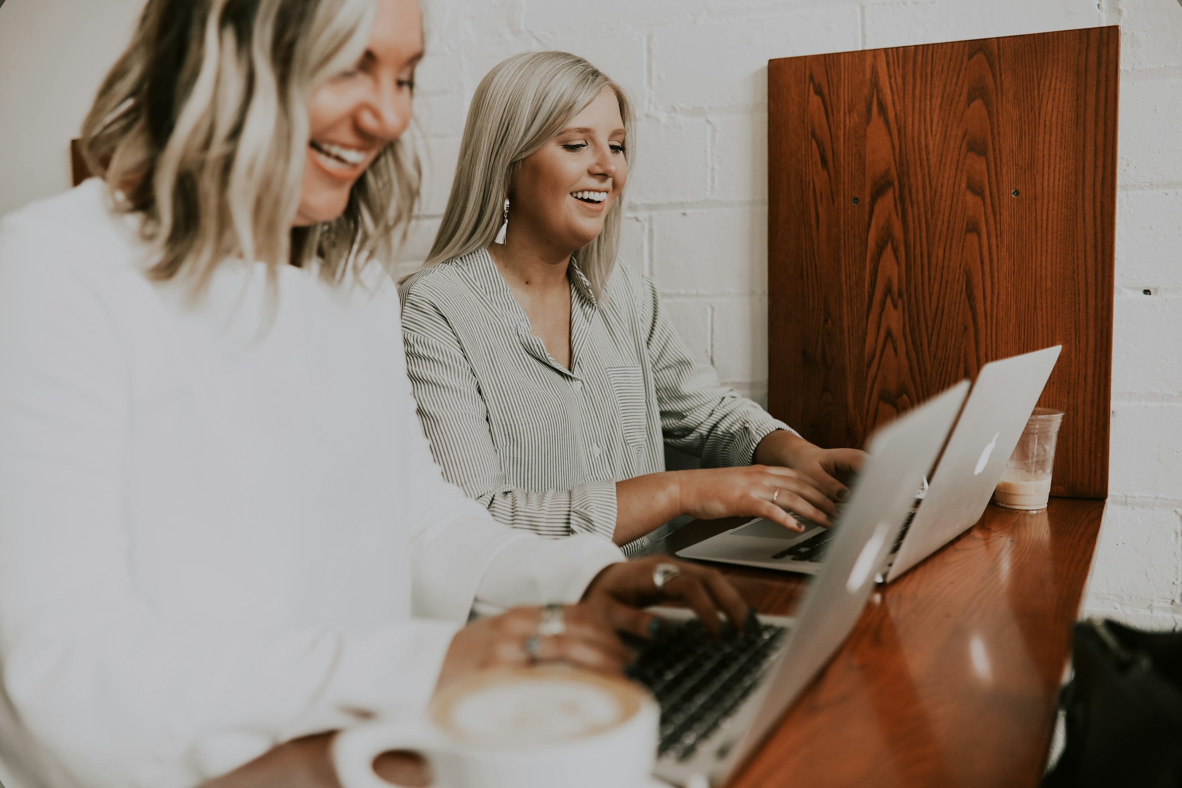 Deux femmes rient en utilisant leur ordinateur portable dans un bureau | Source : Unsplash