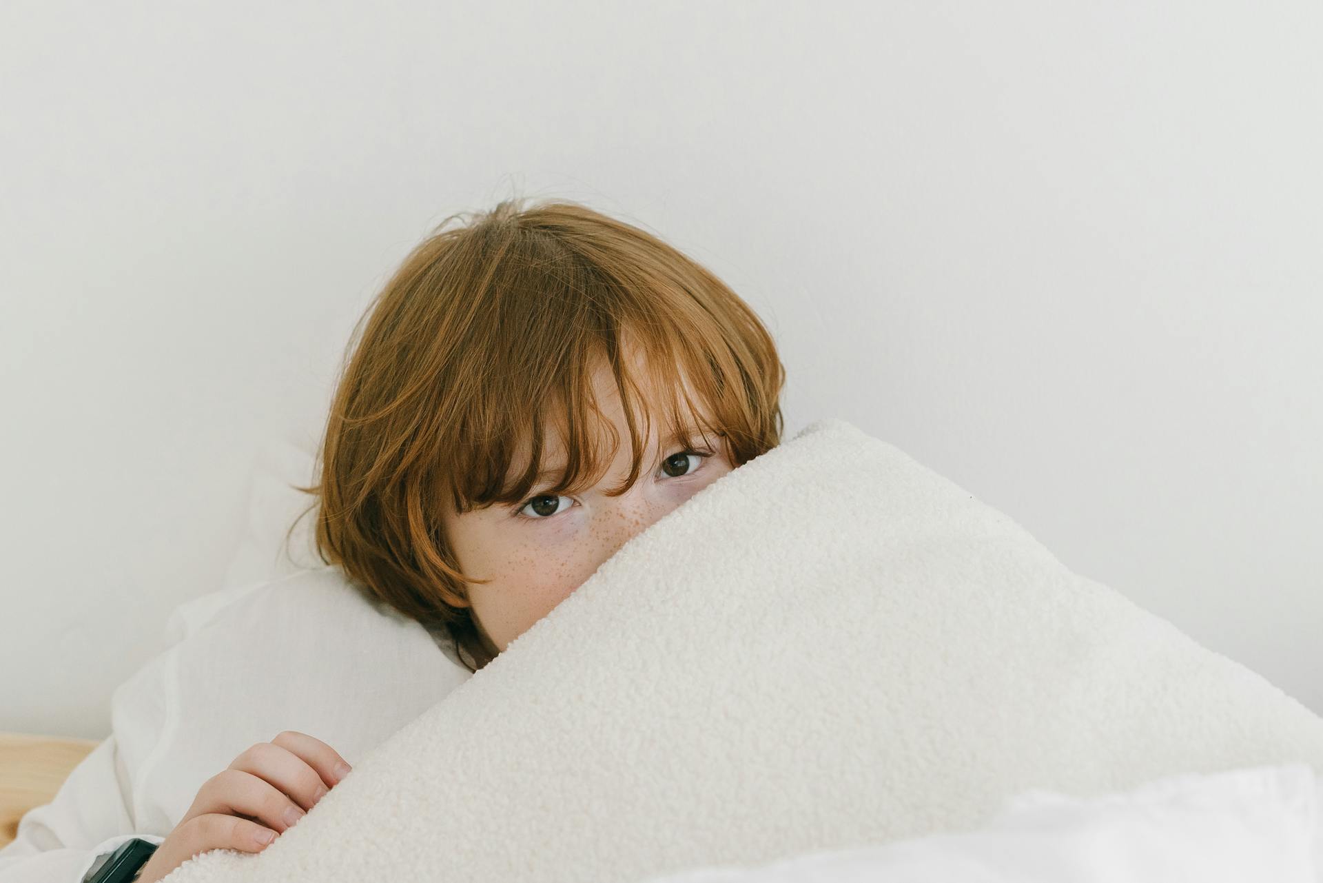 Un garçon allongé sous sa couverture | Source : Pexels