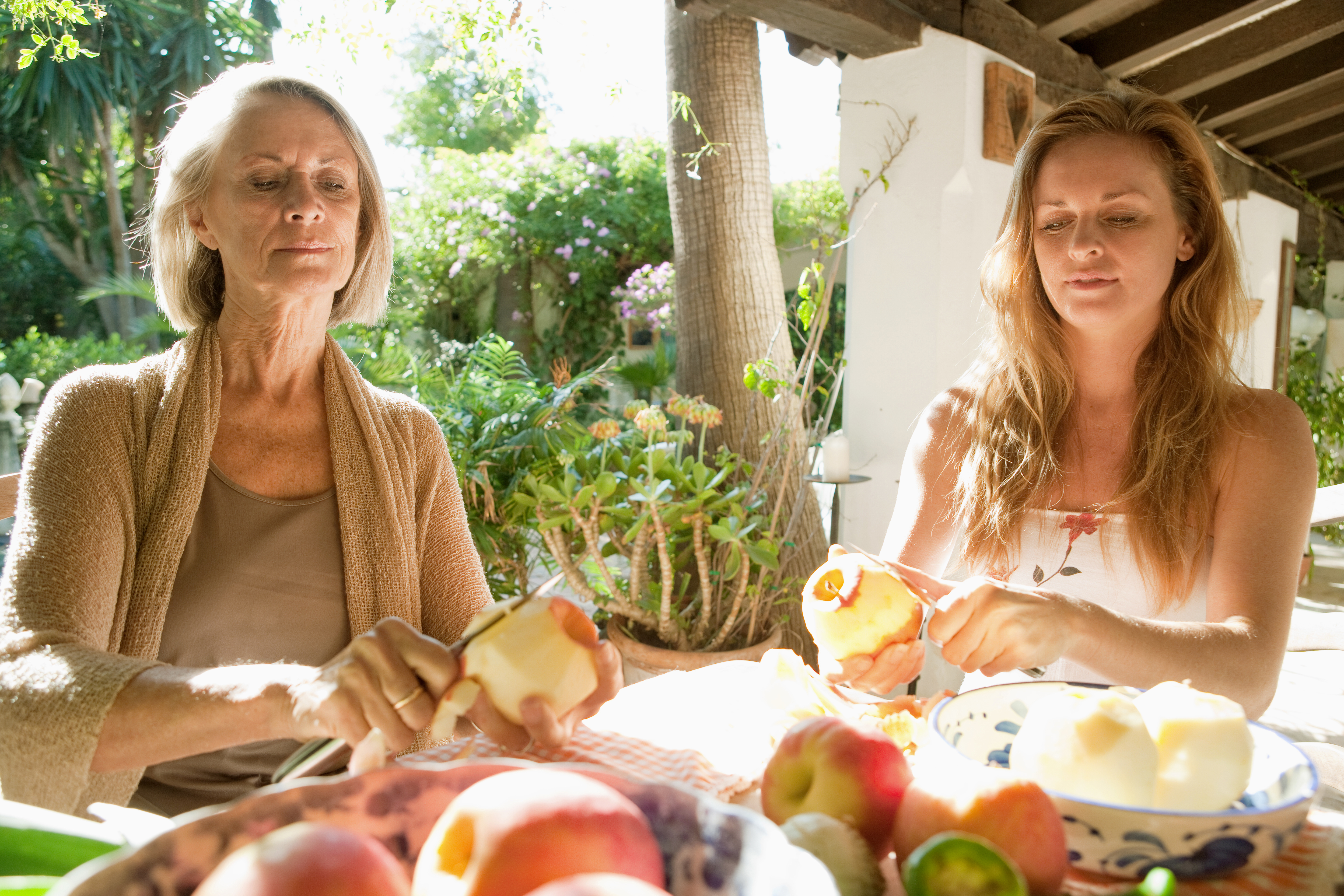 Deux femmes à une table à manger en train d'éplucher des pommes | Source : Shutterstock